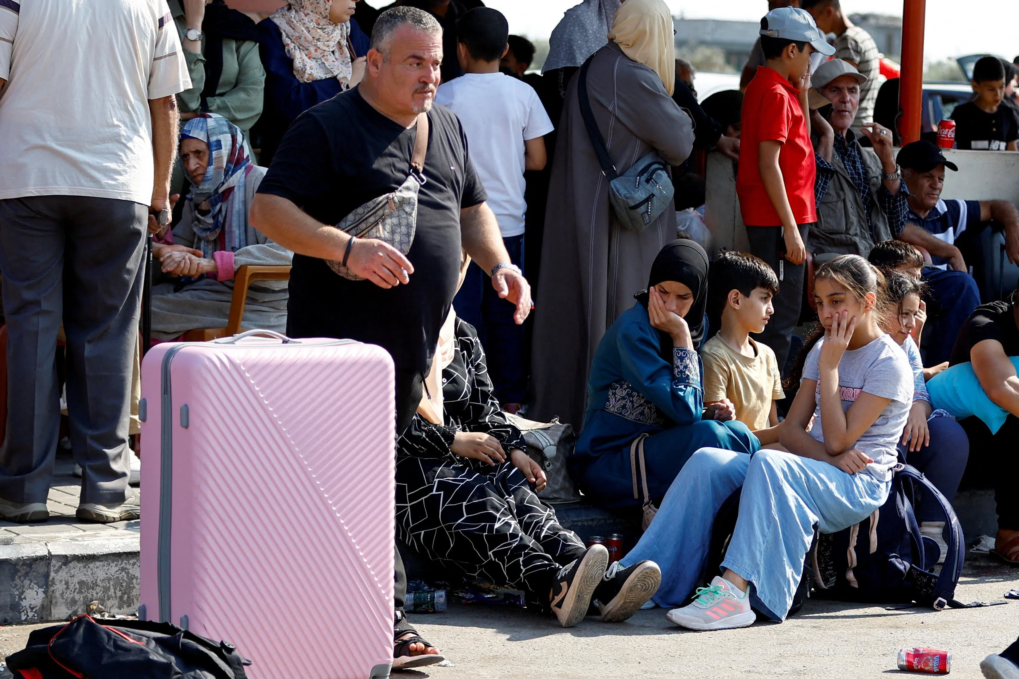 10月14日，拥有双重国籍的巴勒斯坦人在加沙南部拉法市（Rafah）与埃及的过境通道等待获准进入埃及避难。（路透社）