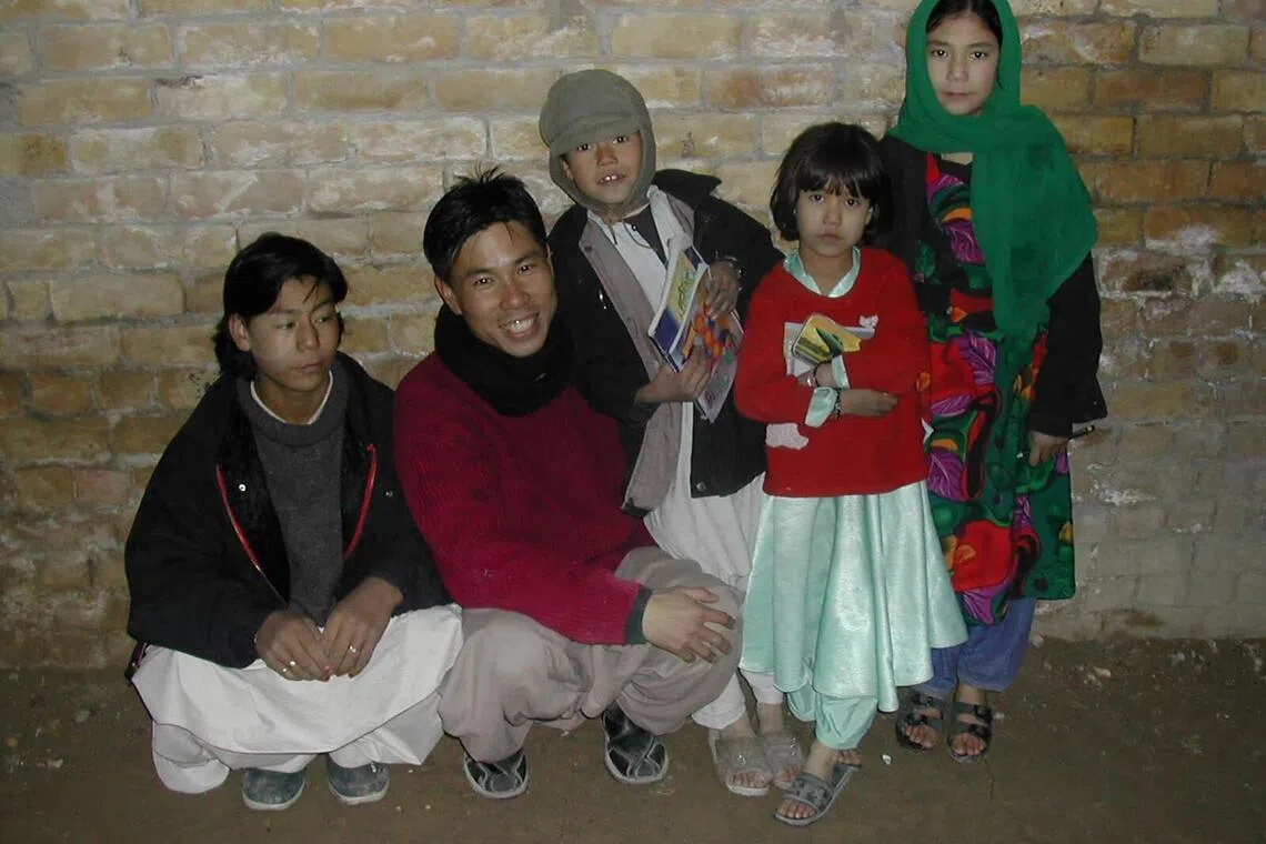 王德扬与阿富汗难民儿童在一起，分发冬衣给他们过冬。（受访者提供）