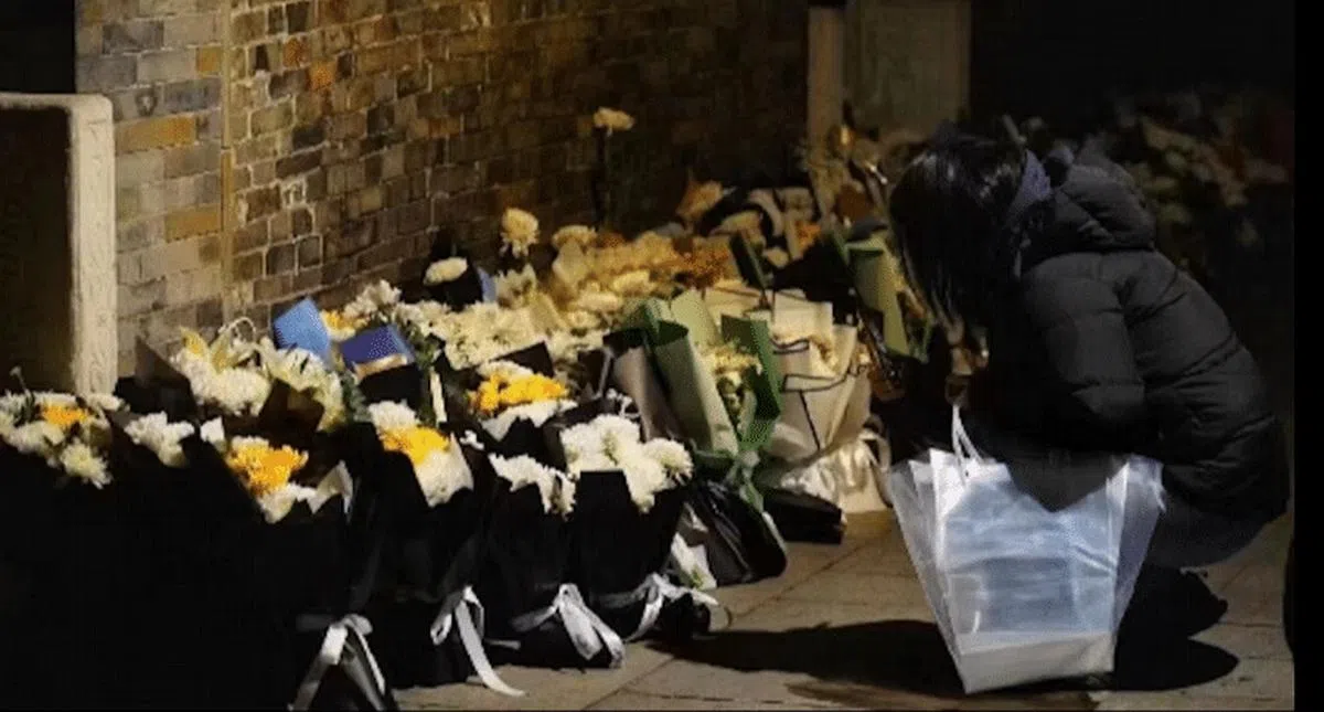 一名民众在江泽民故居外摆放鲜花。（香港01）