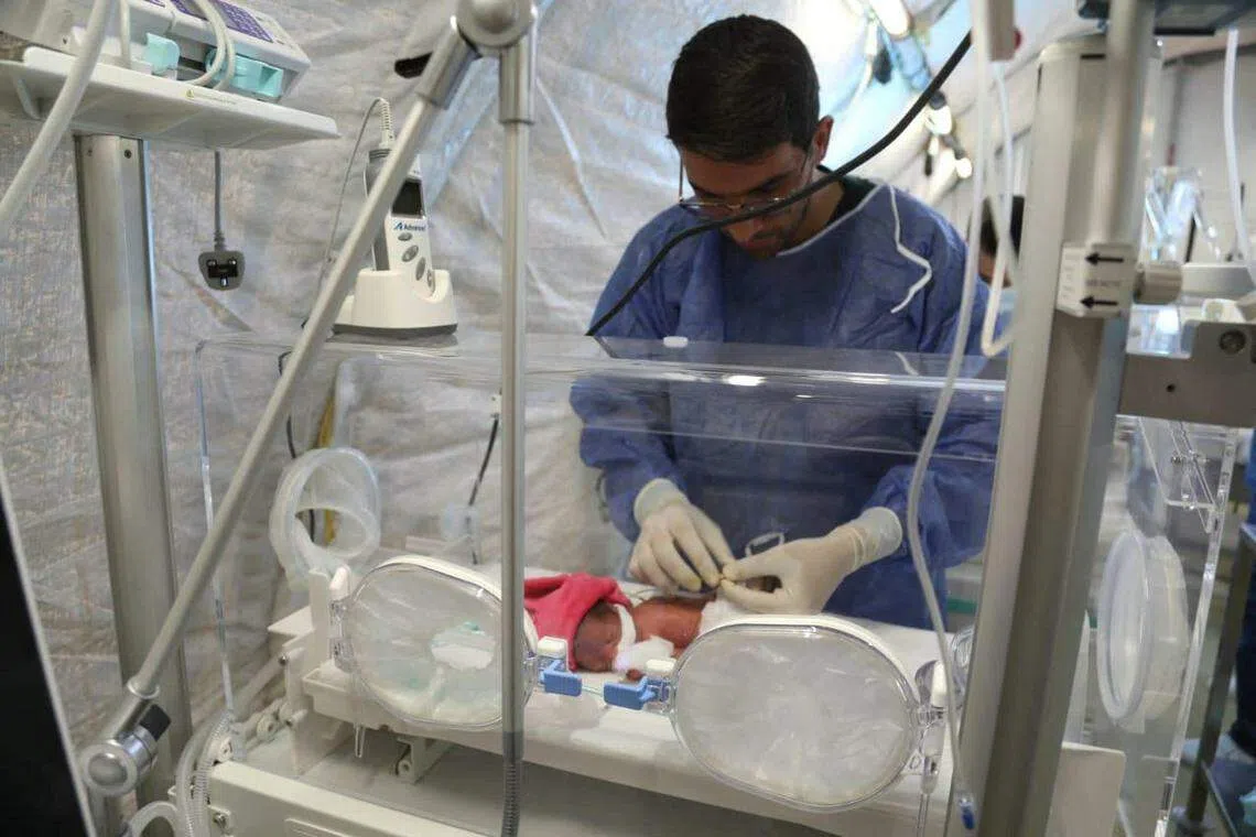 加沙战火重燃，局势再次紧张。在加沙的约旦野战医院内，医护人员细心照顾保温箱里的一名早产儿。（路透社）