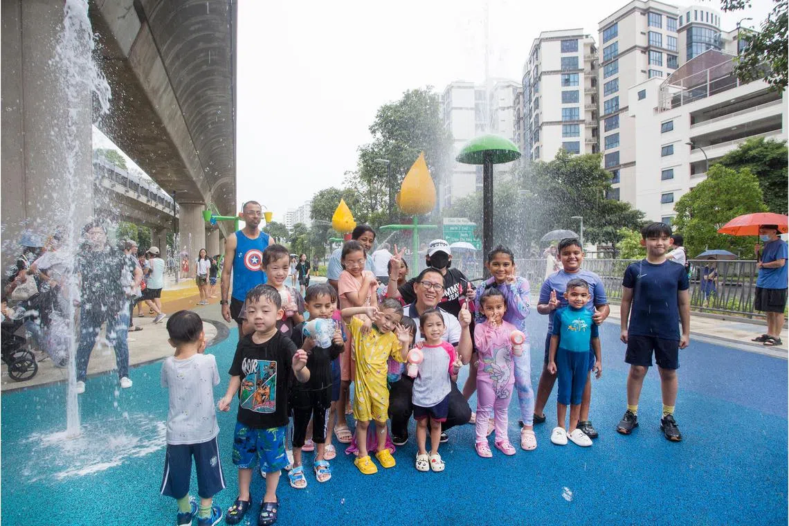 任梓铭（中）在靠近油池地铁站的水池游乐区，与前来玩水的孩子们合照。（马西岭—油池市镇理事会提供）