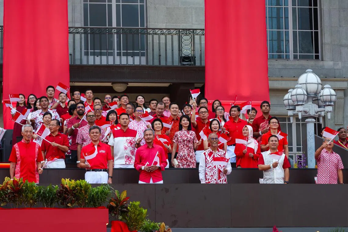 国务资政李显龙（第一排左起）、公共服务统筹部长兼国防部长陈振声、外交部长维文医生、社会及家庭发展部长马善高、教育部长李智陞，以及律政部长兼内政部第二部长唐振辉，与国会议长谢健平（第二排左一）和国会反对党领袖毕丹星（第四排左二）等政务官和国会议员挥舞着国旗，与全民同庆建国60周年。（林明顺摄）