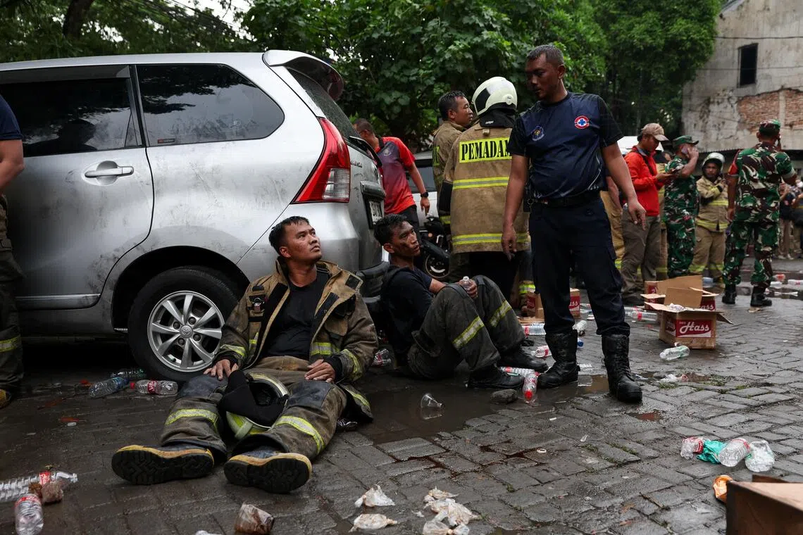 雅加达消防局派出至少100名消防员和29辆消防车前去灭火。精疲力尽的消防员坐在火场旁轮流休息。（路透社）