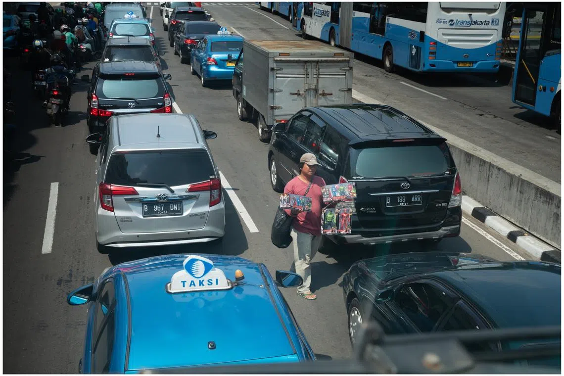 街头小贩拎着玩具，穿梭在繁忙的车流之间。（姚耀光摄）