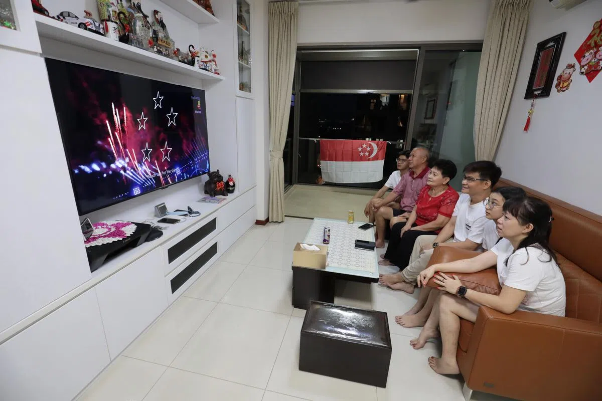 通过增强现实（AR）技术，像陈明基（左二）一家在屏幕前的观众，能看到五颗闪烁的星星缓缓升起，带着新加坡的愿景飞向未来。（林国明摄）