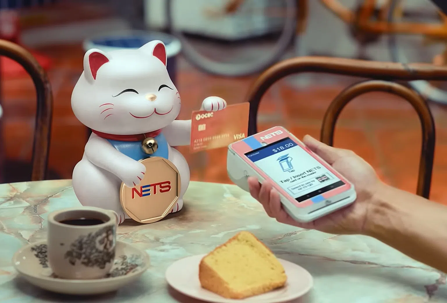 “NETS Tappy Cat”活动借由招财猫的“招牌动作”，展示在日常生活中任何场景如到咖啡店用餐——使用NETS进行免接触数码支付是如此简单。（图/NETS提供）