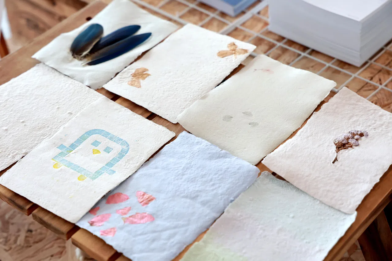 手工纸装饰用的材料如羽毛和干花，都蕴含环保减废精神。（龙国雄摄）