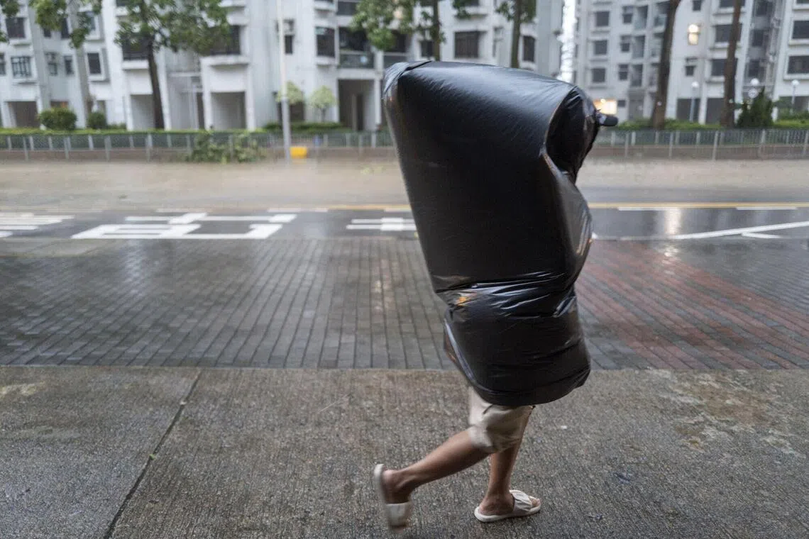 一名行人在杏花邨住宅区身披垃圾袋避雨。（彭博社）