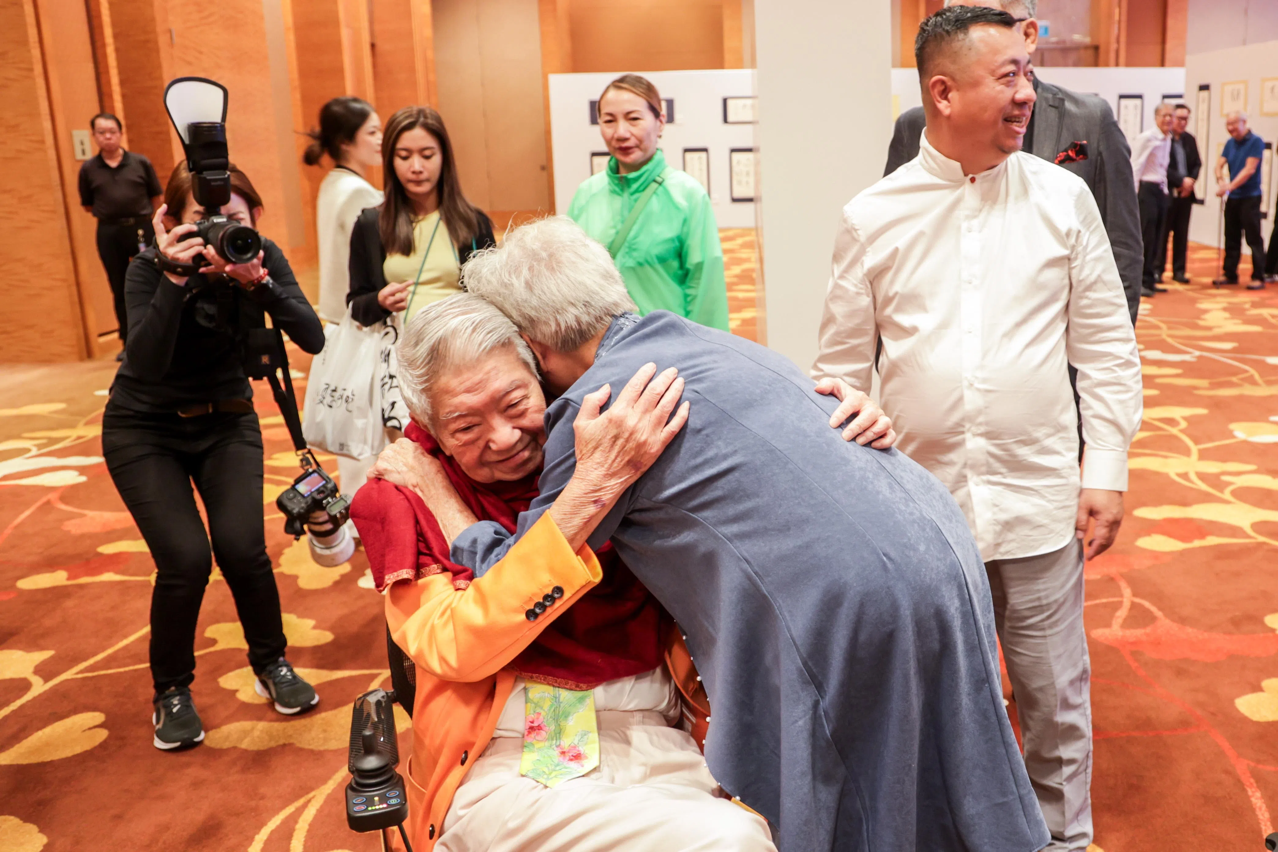 阔别五年，前校长蔡亮从轮椅上起身拥抱弟弟蔡澜。（叶振忠摄）