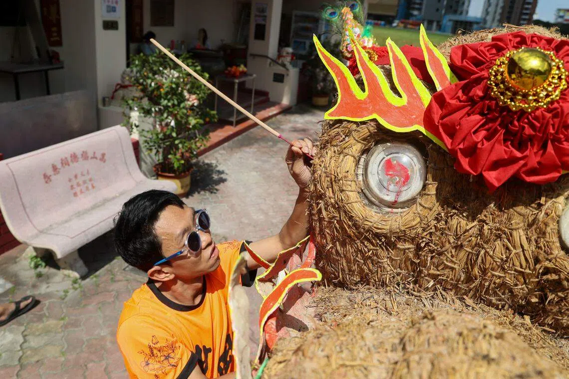 甄俊杰示范以45度斜角将香支插到稻草火龙身上。（卓祾祎摄）