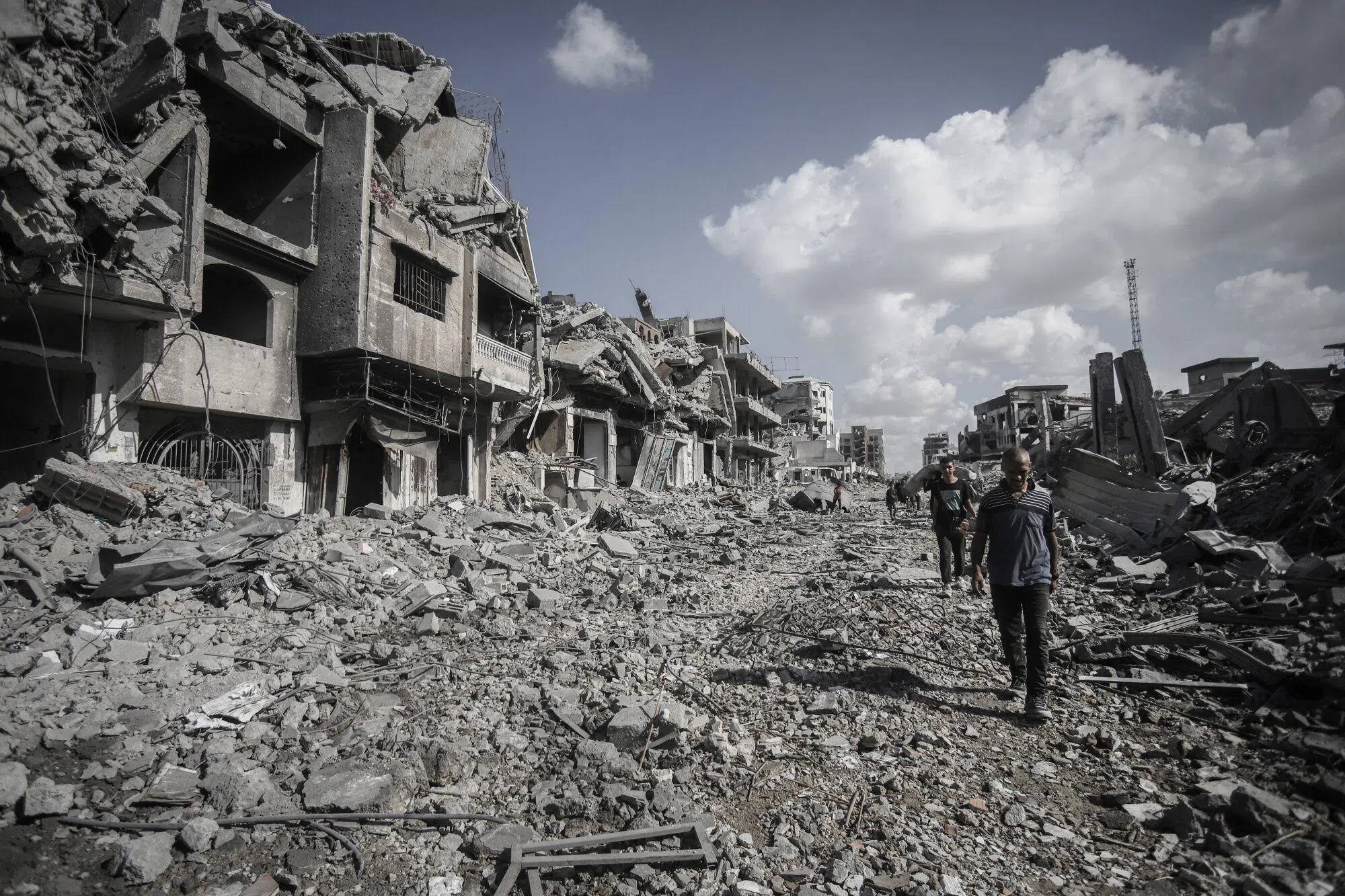 10月10日，人们在加沙城一条两旁尽是废墟的街道上前行。（彭博社）