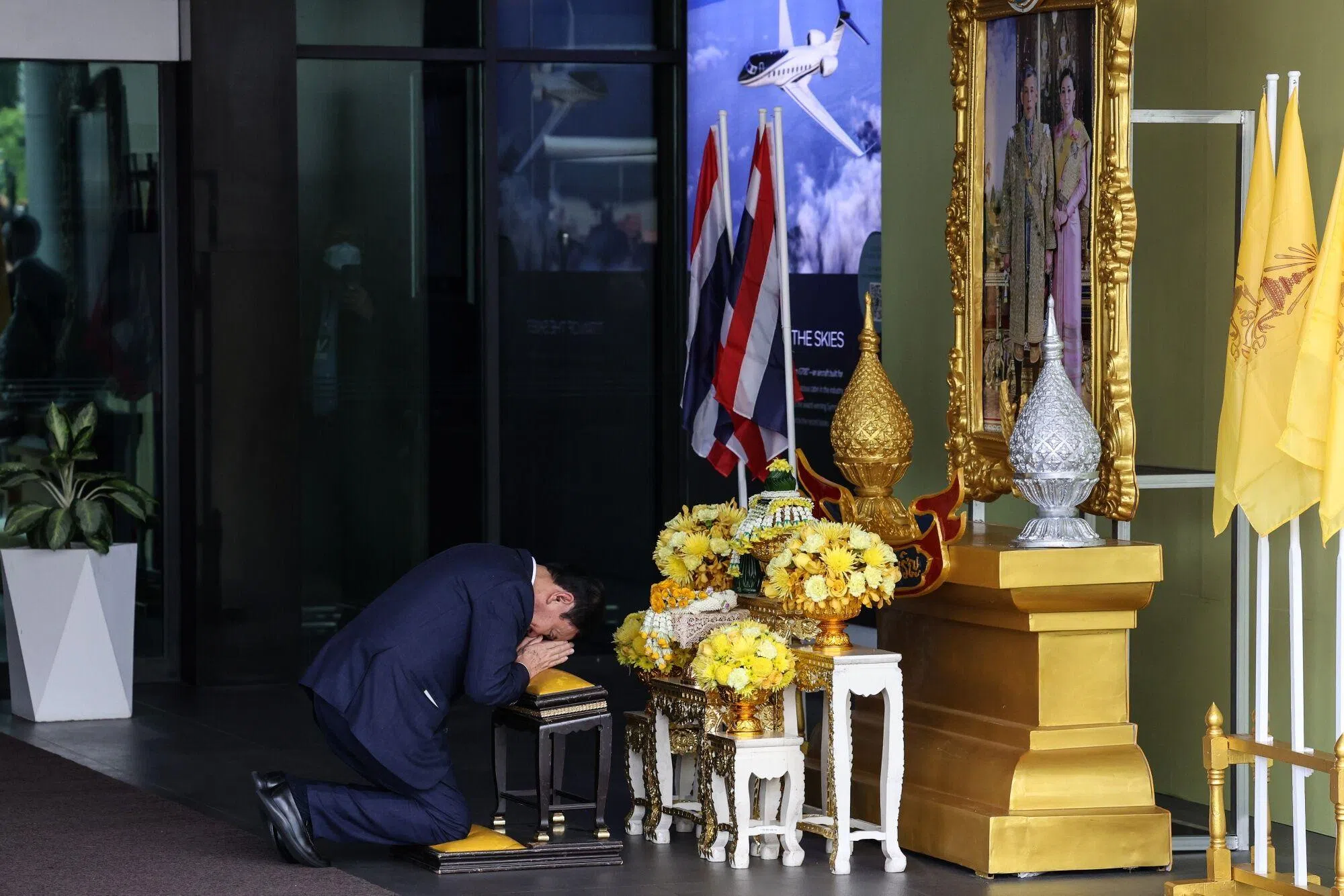 达信在曼谷廊曼国际机场向泰王哇集拉隆功的肖像跪拜致意。（彭博社）