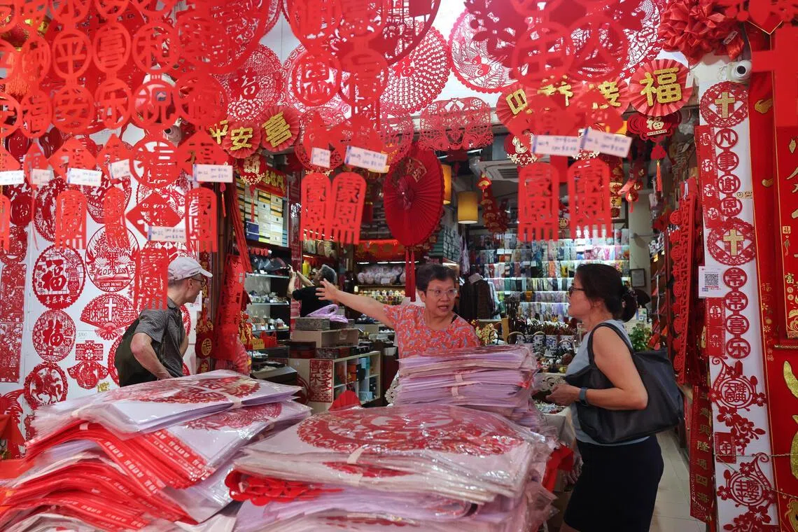 赵洪敏（中间，穿橘色上衣）每年都会从中国工厂定制符合本地习俗的新春窗花剪纸。今年她感觉行情不好，刻意减少了三成订单。（唐家鸿摄）