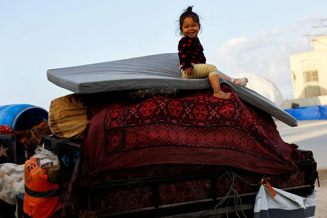 以哈达成停火协议后，被迫从加沙北部疏散到南部的加沙人开始尝试回家。图为一名女童坐在堆满杂物的车辆上，往回家的方向走。（路透社）