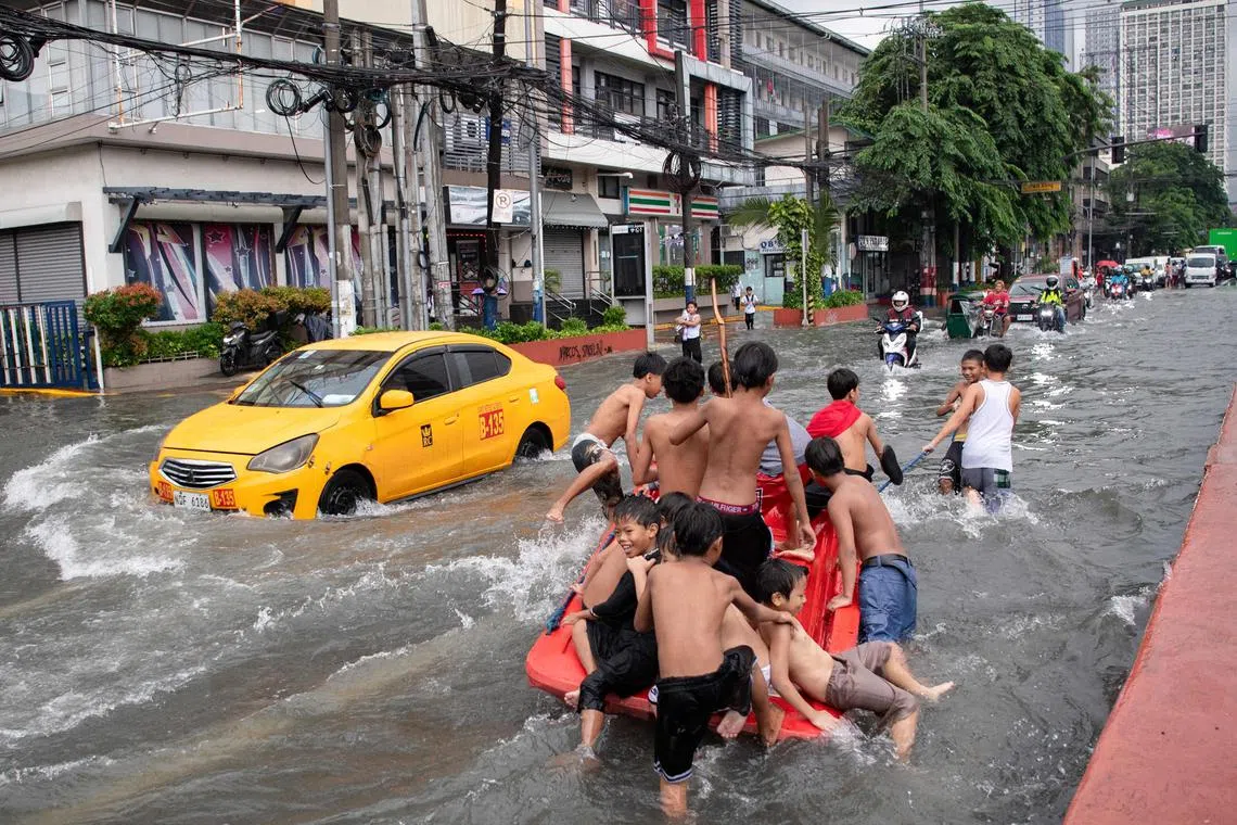 台风“韦帕”虽已离开菲律宾，但当地部分地区仍继续下着暴雨，洪水泛滥。一群孩童星期一（7月21日）拖着小船，在首都马尼拉淹水的街道上玩耍。（法新社）