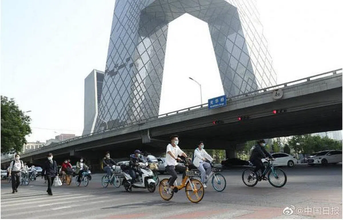 北京市民昨天骑车经过中央电视台大楼。（中国日报）