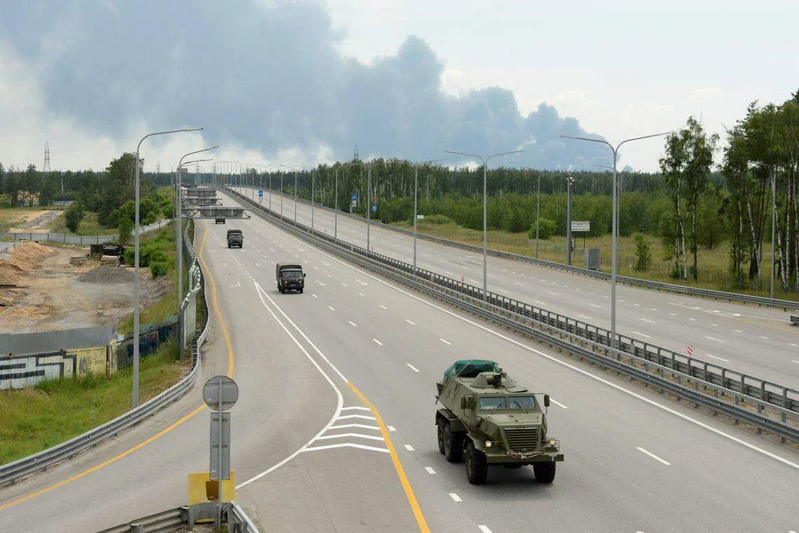 瓦格纳6月24日发动兵变当天，它的一列车队在沃罗涅日市附近的快速公路上行驶。后方的储油库起火，冒出滚滚浓烟。（路透社）