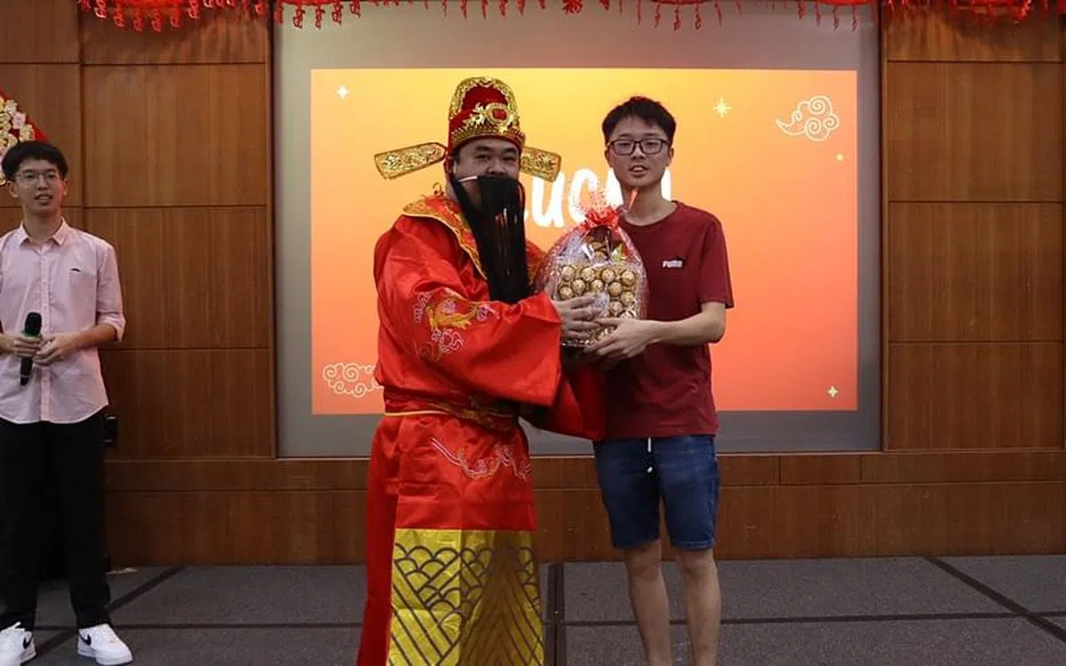 由老师扮演的财神爷进行幸运抽奖，学生高兴地上台领取礼包。（周文靖摄）