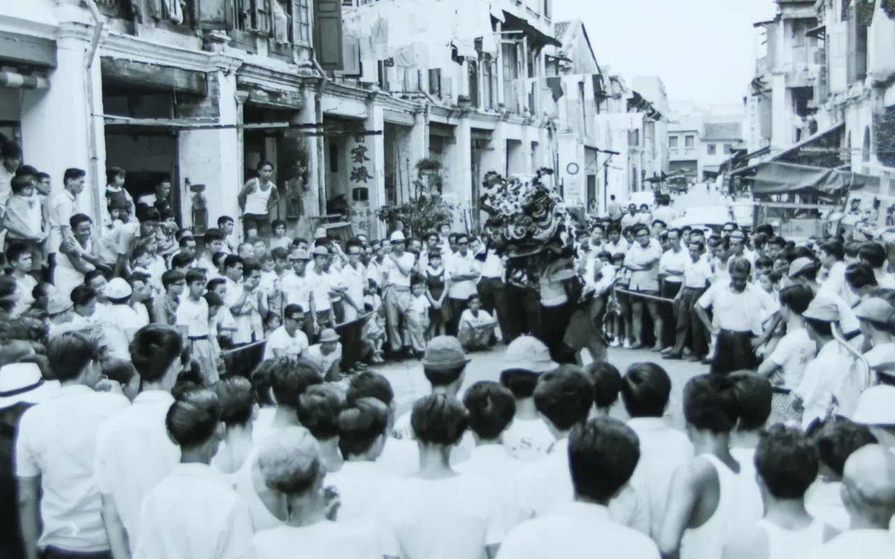 1968年元宵节，鸿胜馆醒狮团在黑街（武吉士街）破“佛门阵”，吸引众多民众围观。（受访者提供）