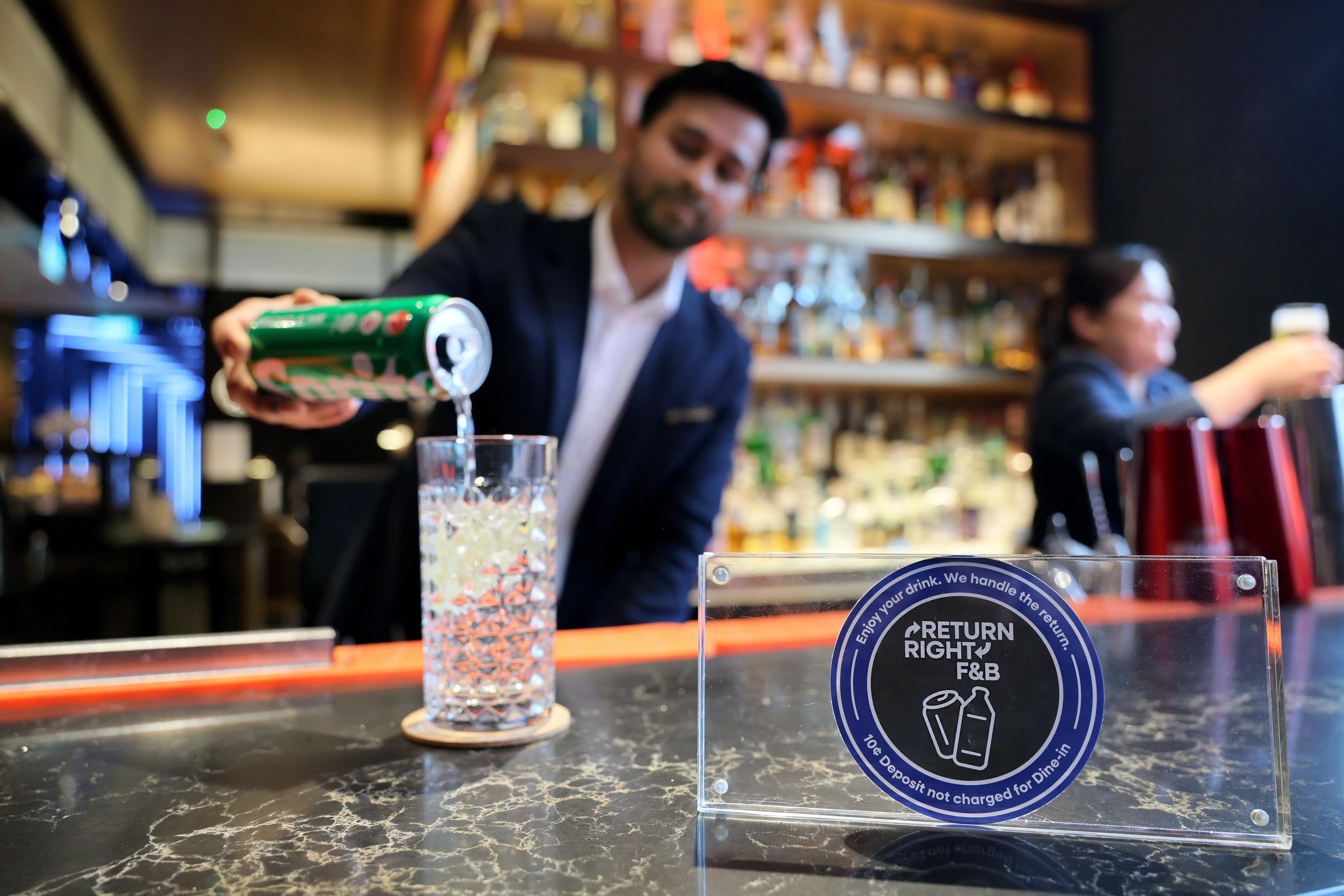 乌节路铂尔曼酒店的服务员通常会先把饮料倒入玻璃杯再送上桌，瓶罐便可在后端直接回收。（龙国雄摄）