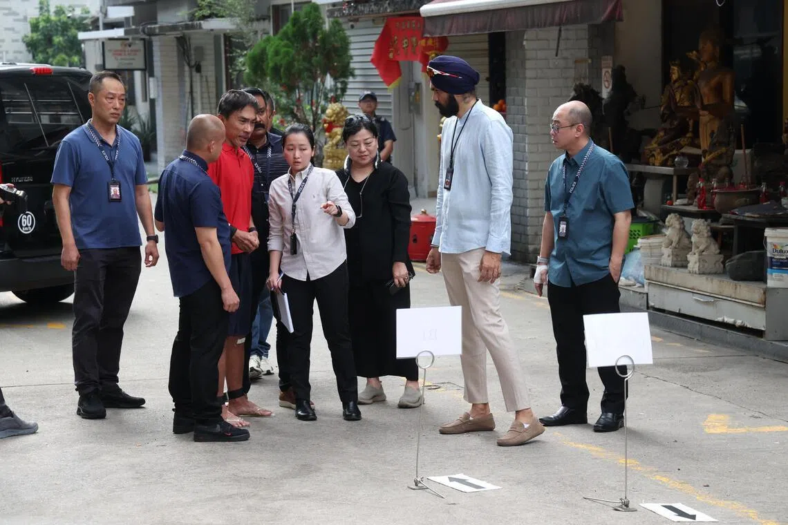 嫌犯王侯昌（红衣者）在善缘古佛社外，向警方指认案发现场。（郑一鸣摄）