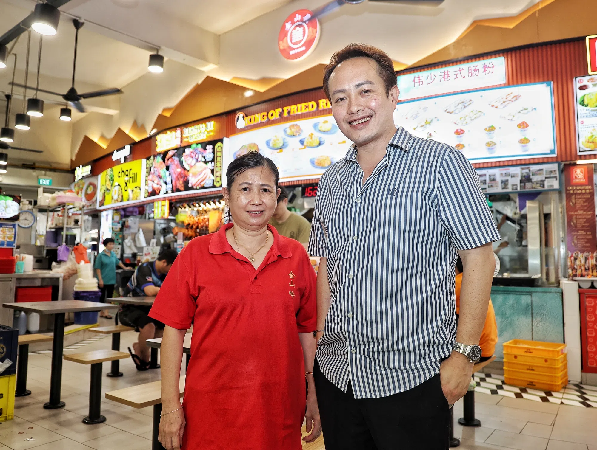 金山岭饮食集团主席洪启强（右）和咖啡店主管王绣莲，向记者介绍在武吉班让环路第259座的咖啡店有哪些经济选项。（徐颖荃摄）