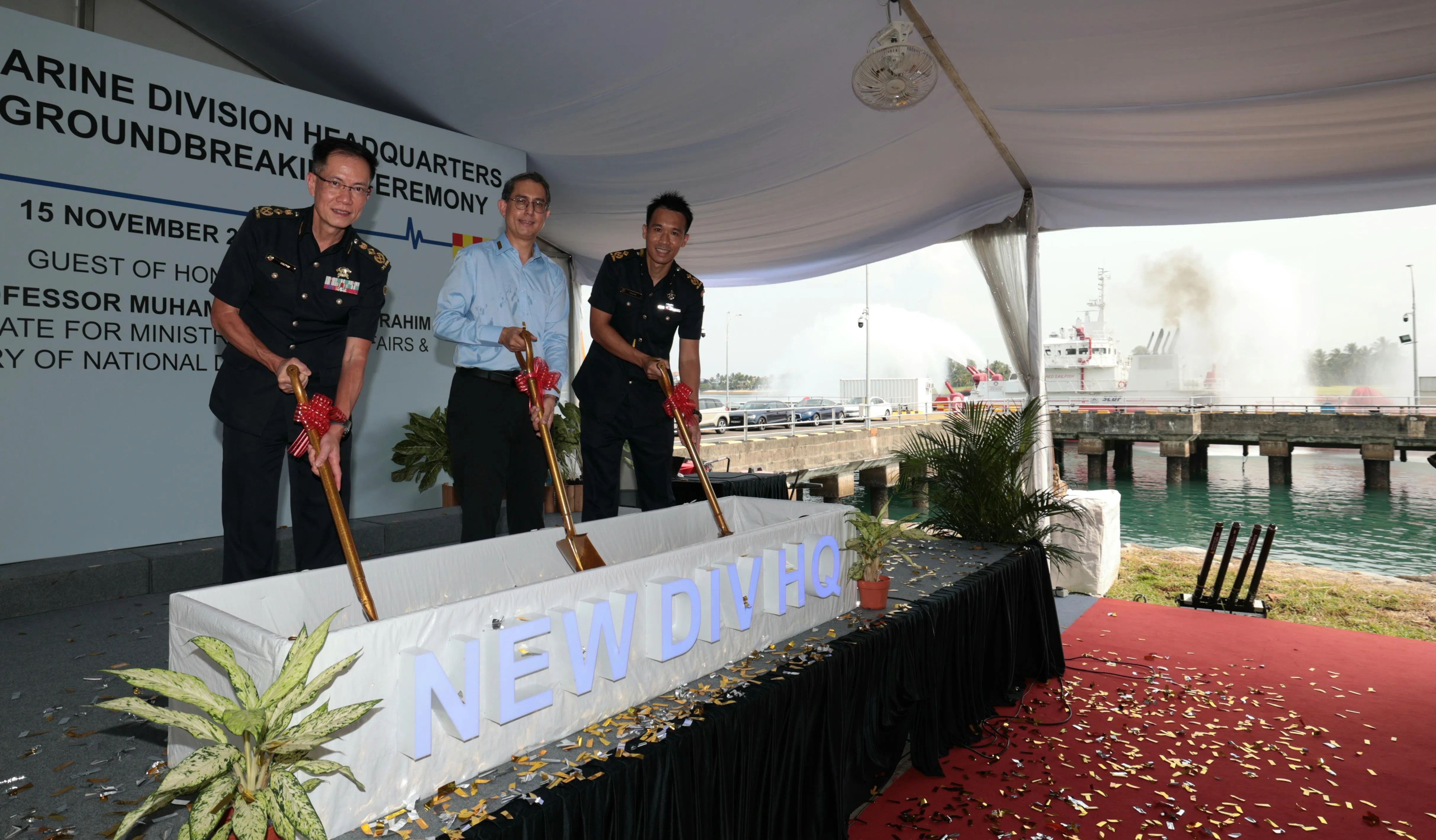 内政部兼国家发展部政务部长费绍尔副教授（中）主持民防部队海事消防分区总部动土仪式，同时间右边海岸的“红旗鱼”（Red Sailfish）重型消防船以水门礼庆祝。民防部队总监叶伟德（左）和民防部队海事消防分区司令王元为助理总监也参与仪式。（梁麒麟摄）