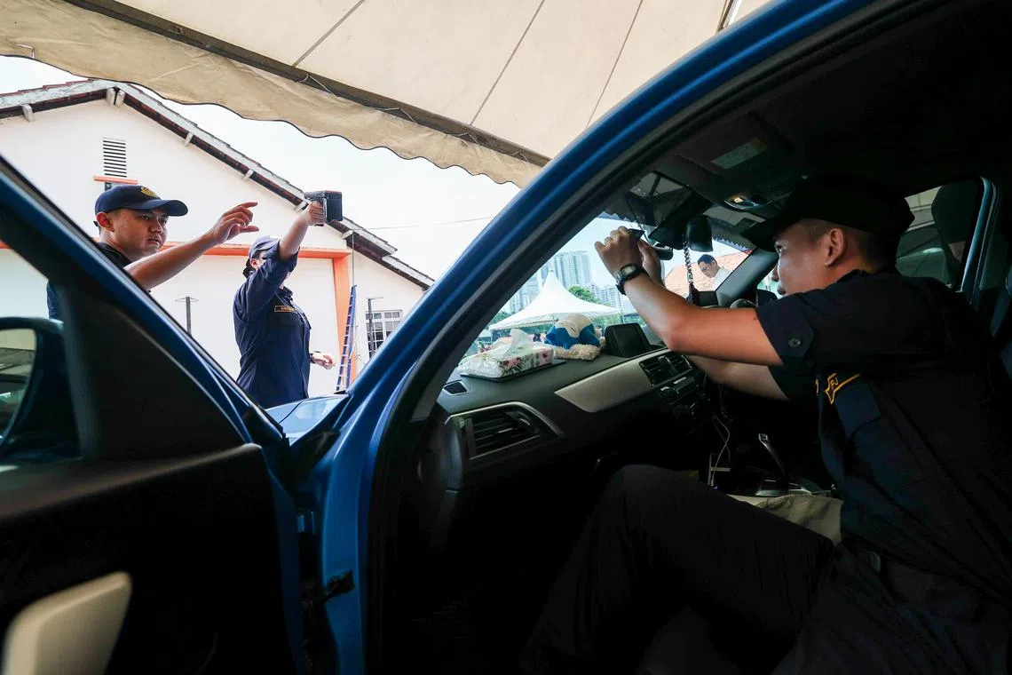 位于新山拉庆旧哥文茶路的南区陆路交通学院，陆交局的官员正在协助车主张贴VEP无线射频识别标签，并用扫描仪测试，确保标签张贴位置合适。（陈斌勤摄）