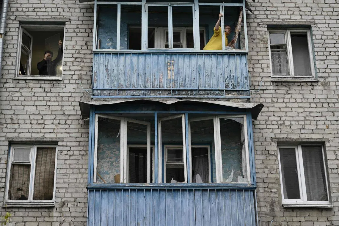 10月25日凌晨，俄罗斯导弹袭击乌克兰首都基辅后，一栋居民楼的居民清理窗户上的玻璃碎片。（法新社）