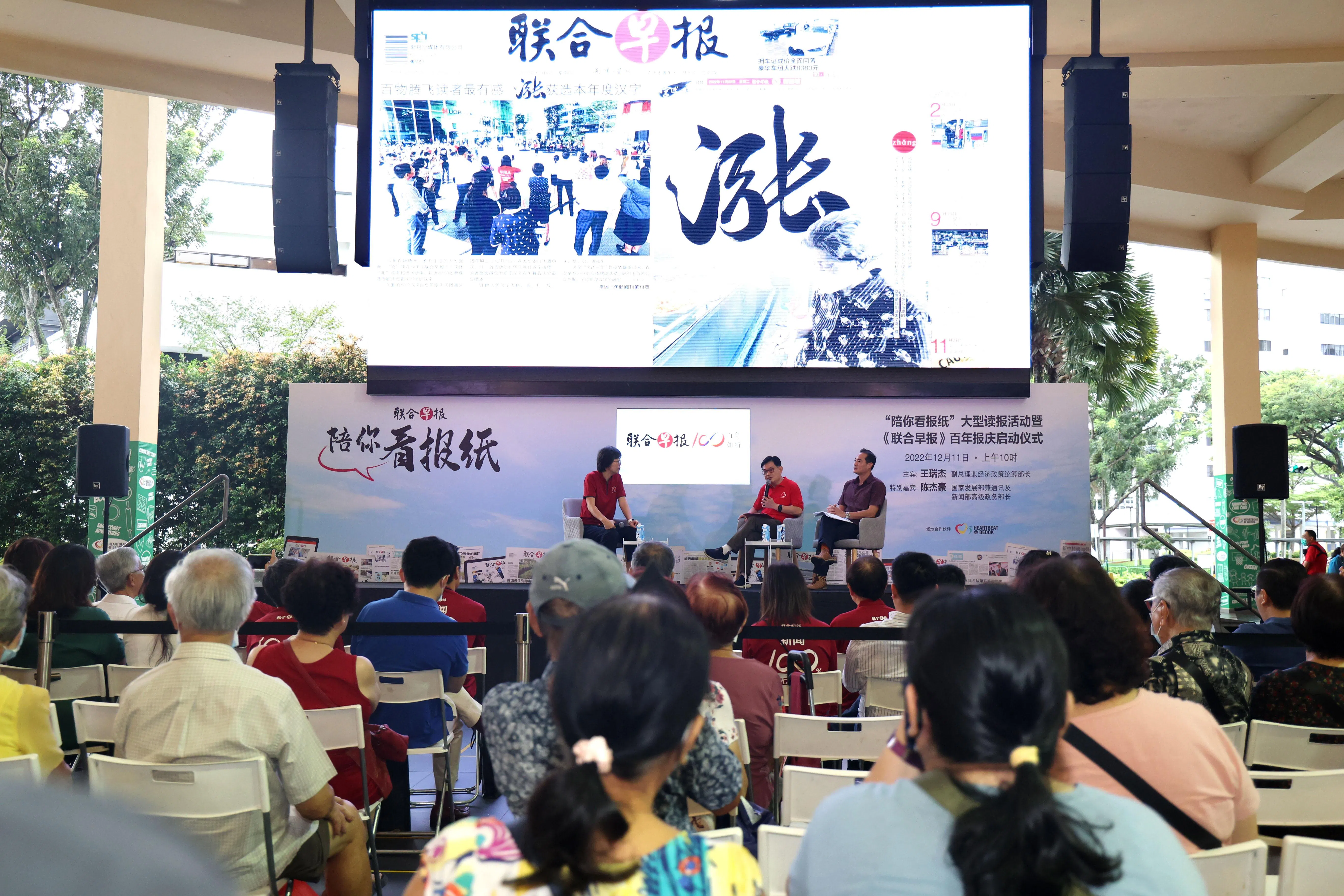 副总理兼经济政策统筹部长王瑞杰（中）和国家发展部兼通讯、新闻部高级政务部长陈杰豪（右），以及新报业媒体华文媒体集团社长李慧玲在场为公众读报，讨论如何应对生活费高涨等课题。（邝启聪摄）