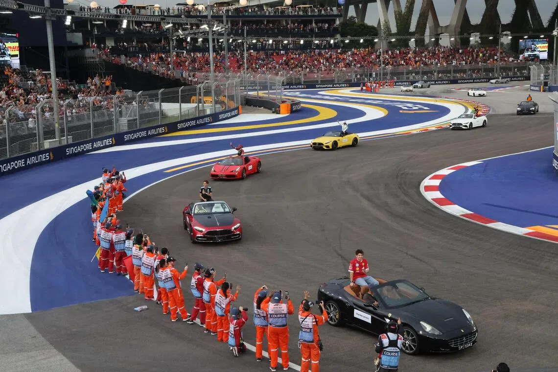 F1车手们在赛前乘坐中古车绕行滨海湾赛道，接受观众和工作人员的欢呼。（唐家鸿摄）