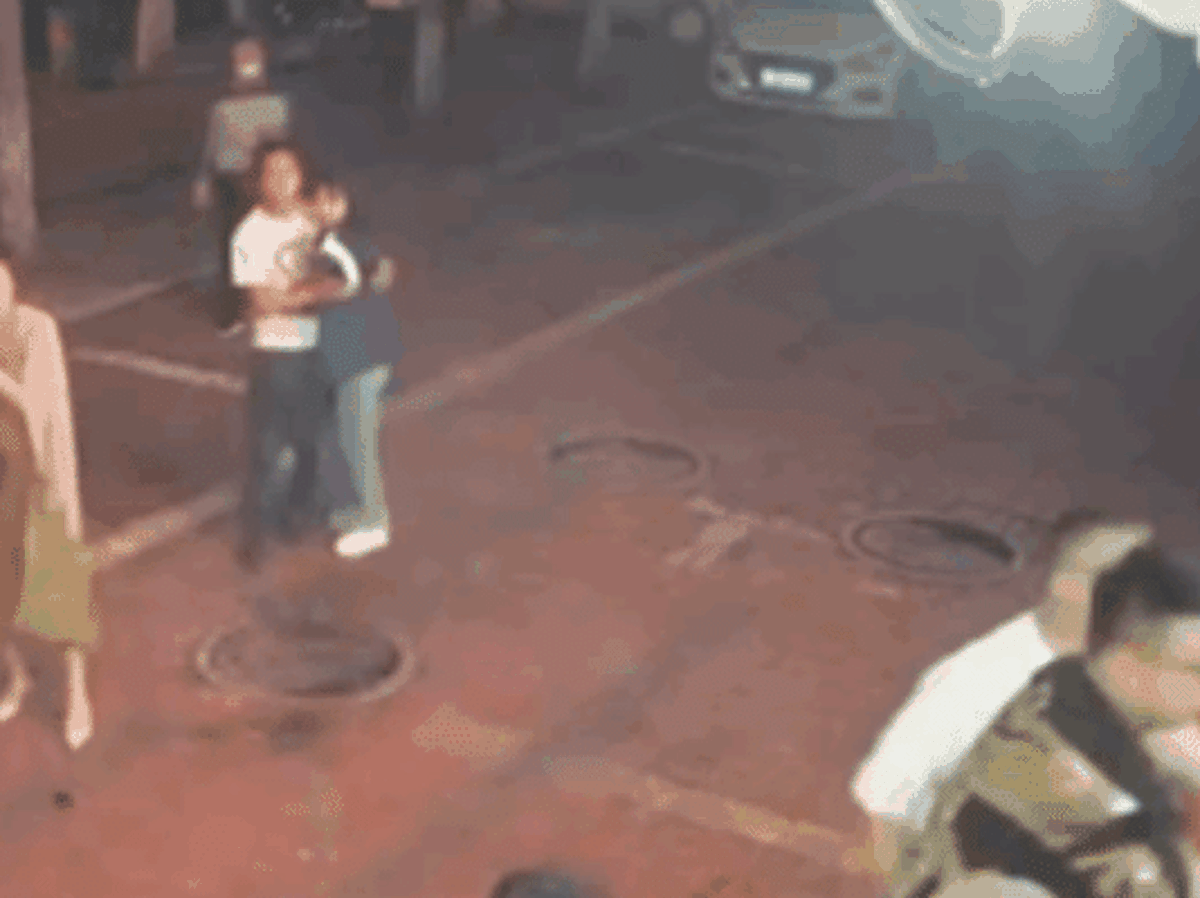 一名蓝衣女子本想上前阻止施暴者打人，但被男友抱住。（互联网）