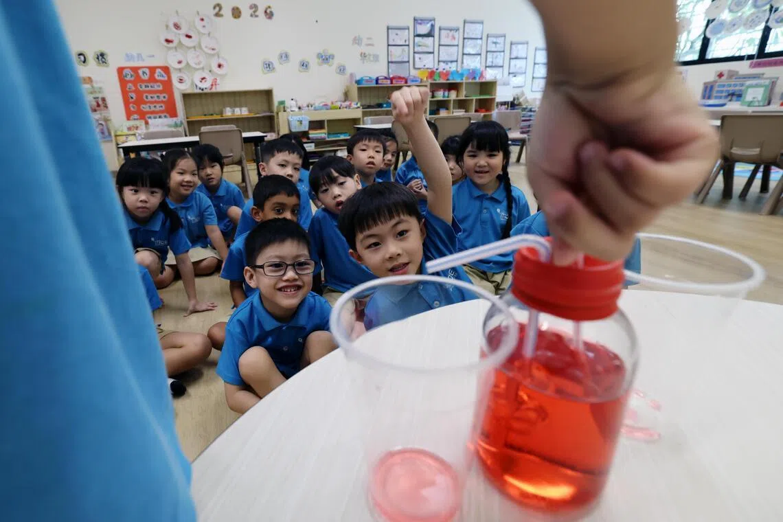 设在后港小学的MK@Hougang教育部幼儿园孩童，在30分钟的母语延伸学习活动中，观察教师利用玻璃瓶和吸管制作的装置，向他们展示心脏泵血的过程。（梁麒麟摄）