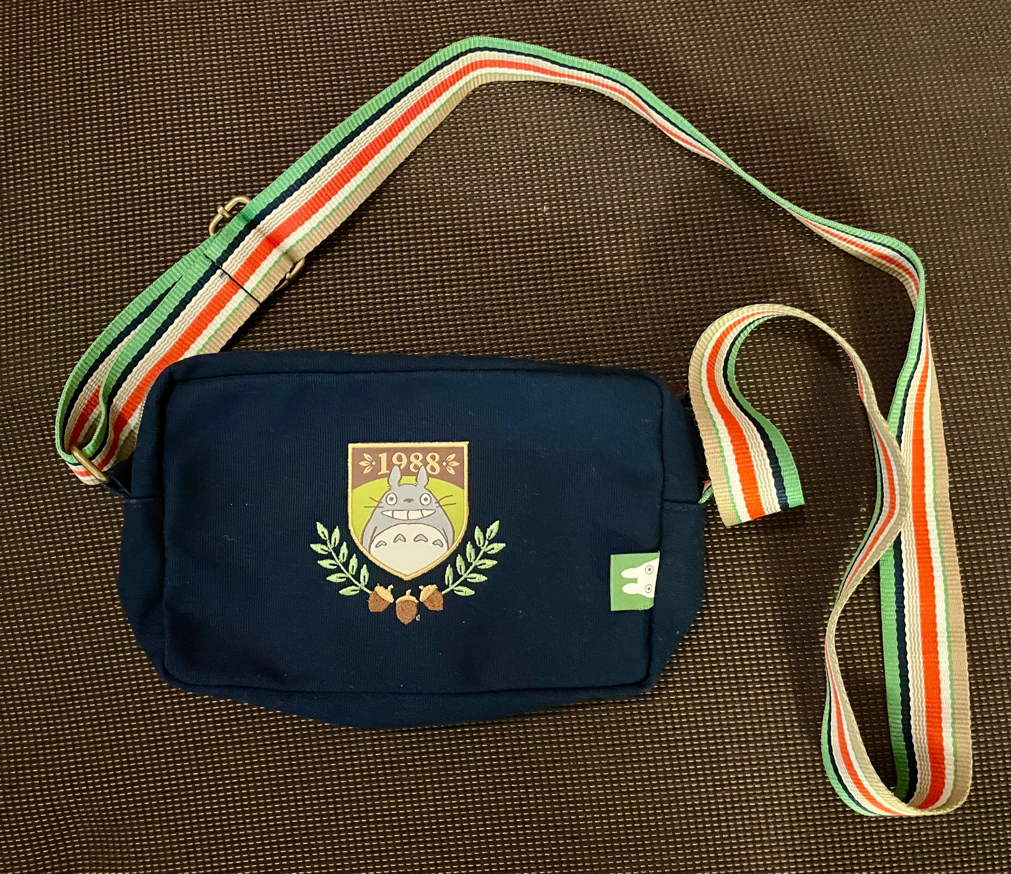 长方形的龙猫肩背包，交叉桂叶构成的校徽图案更添学院风尚。（林方伟摄）