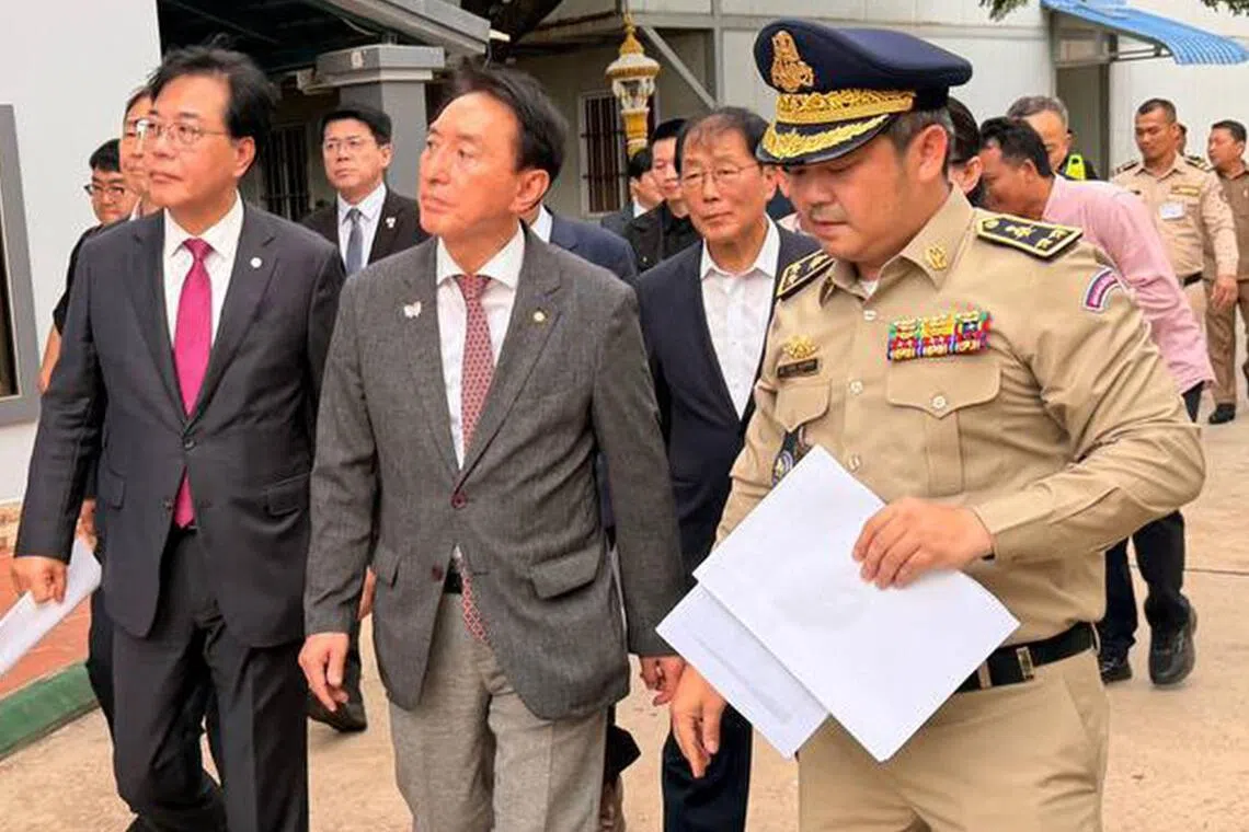 韩国议员金硕基（中）星期三（10月22日）率团到柬埔寨，并由柬埔寨军官带领视察被捣毁的诈骗窝点。（法新社）