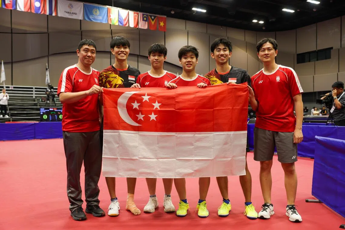 （左起）我国男队主教练高宁、蔡邵恒、黎定龙、郭勇、冯耀恩和周哲宇在赛后手持新加坡国旗合影。（白艳琳摄）