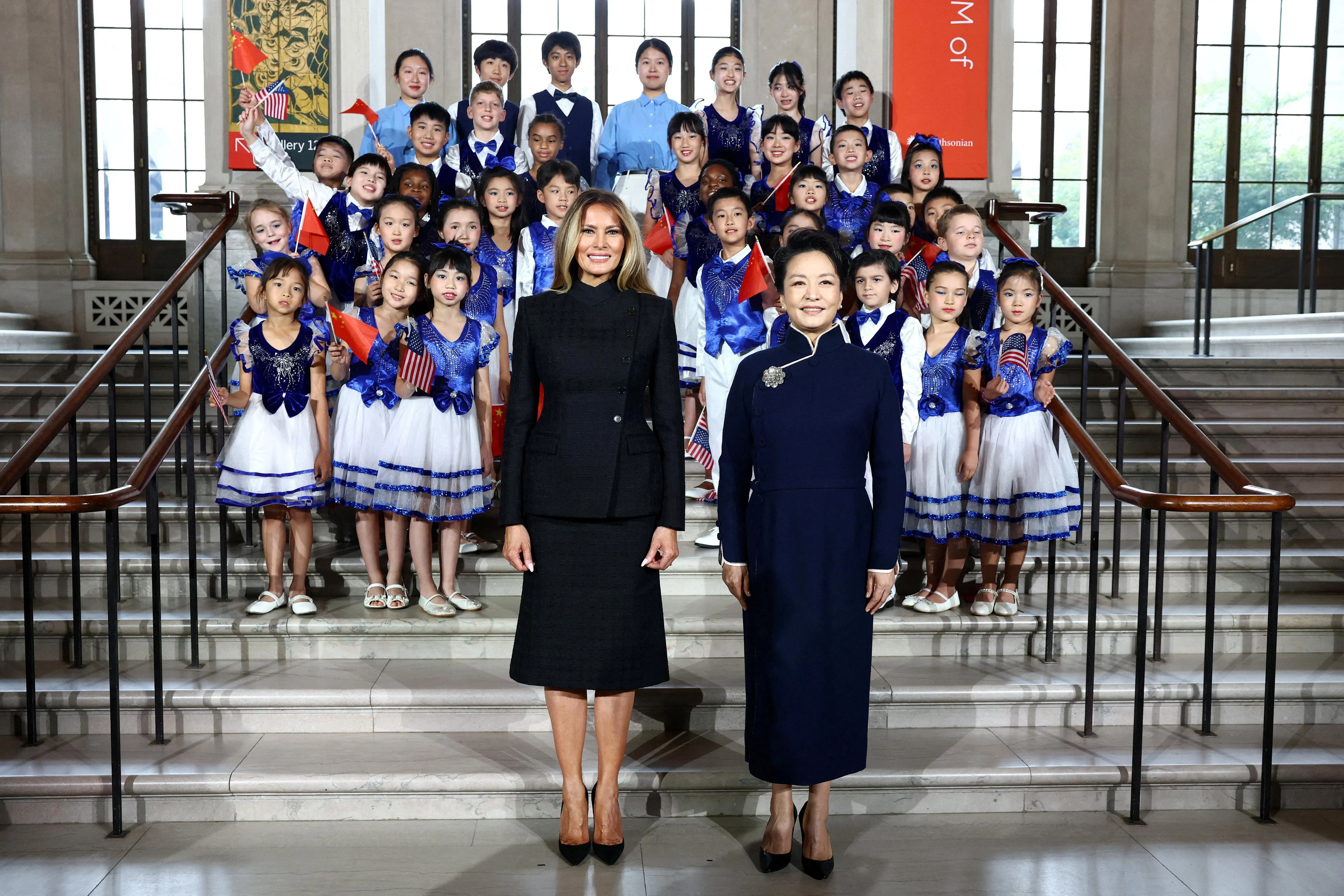 中国国家主席习近平夫人彭丽媛（右）与美国第一夫人梅拉尼娅在华盛顿参观史密森尼国立亚洲艺术博物馆时，与希望中文学校合唱团学生们合影。（路透社）
