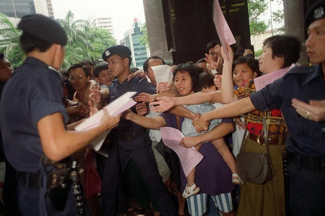 新电信1993年发售优惠股给国人，大批民众当年在银行外排队申请认购股票时向值勤警员领取表格。（档案照片）