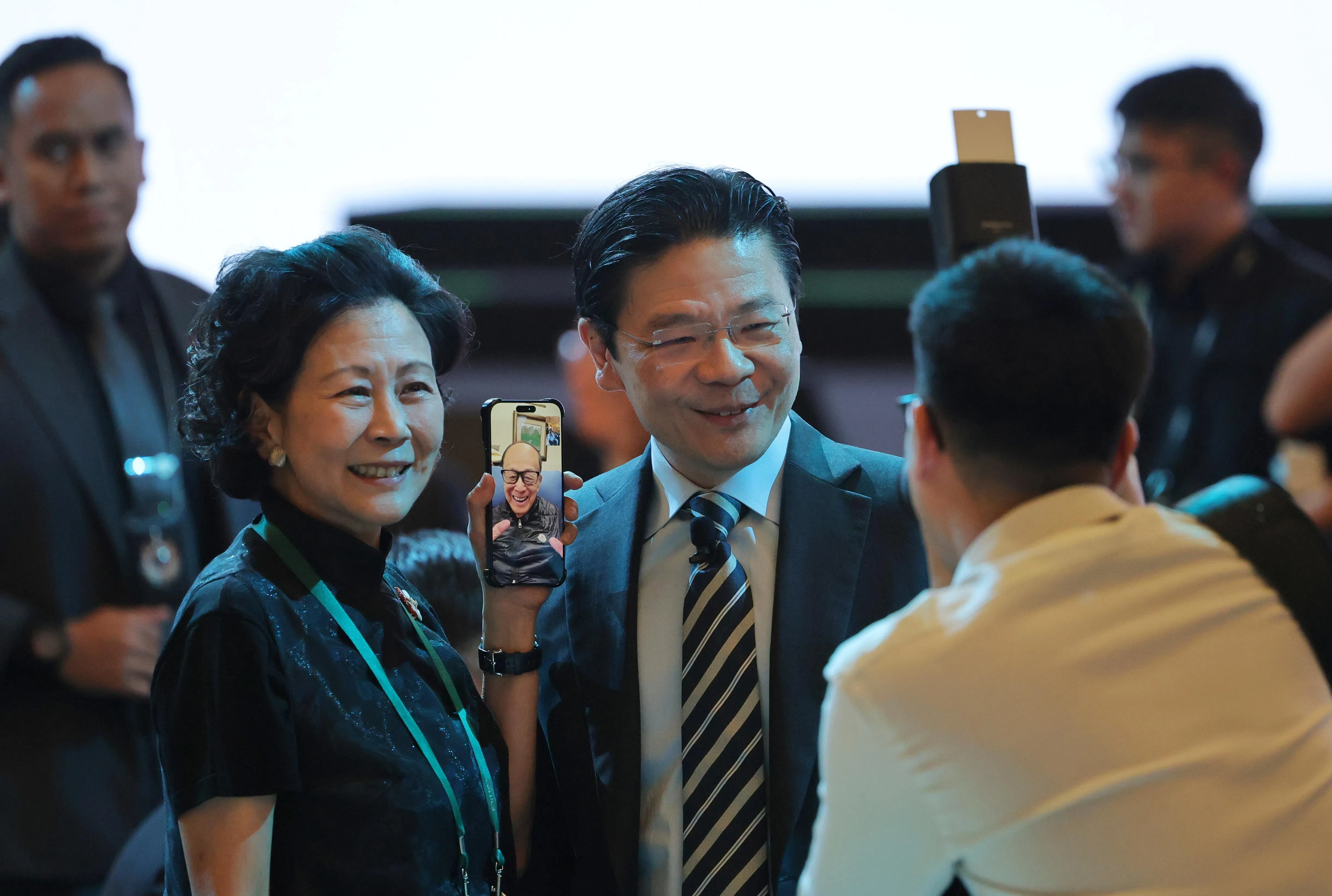 黄循财总理星期四出席福布斯全球总裁会议晚宴，并在席间与多位商界领袖寒暄。维港投资（Horizon Ventures）联合创办人周凯旋（左）其间拨通视讯电话，让黄总理（中间）与香港富豪李嘉诚（手机屏幕）通话。（谢智扬摄）