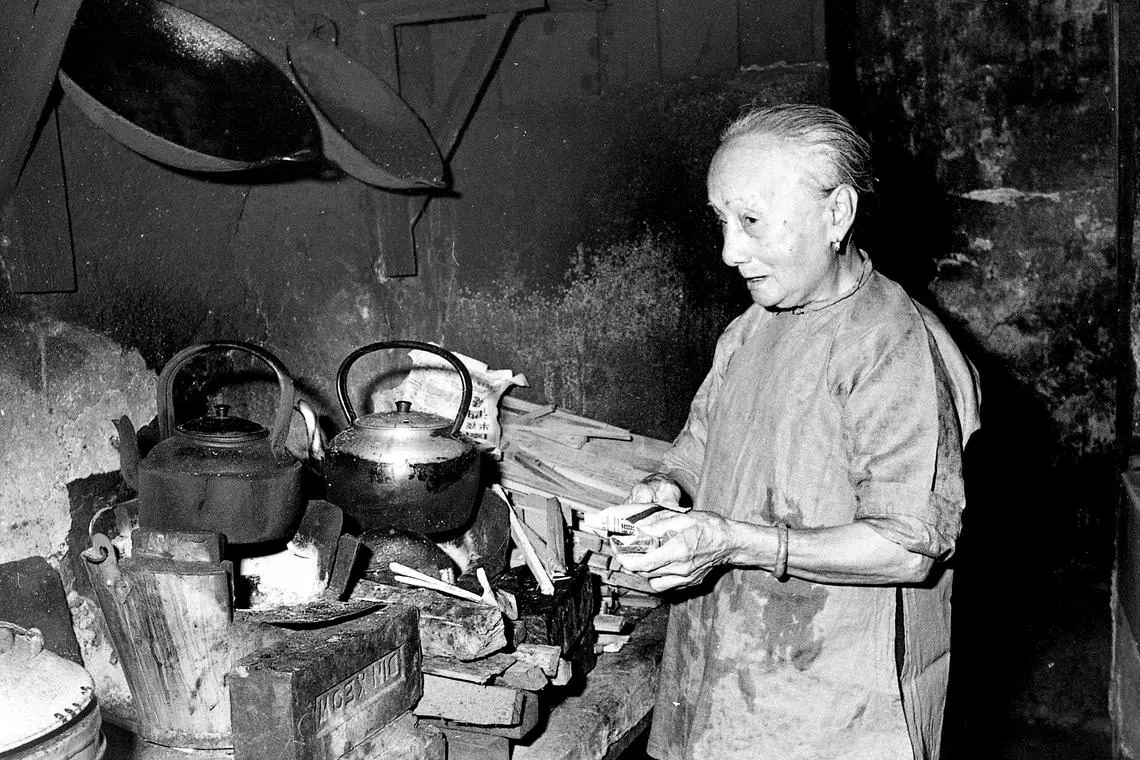 老妇在牛车水五脚基用火炭炉煮开水，此景不再，烧黑的水壶是沉淀的岁月。（档案照）