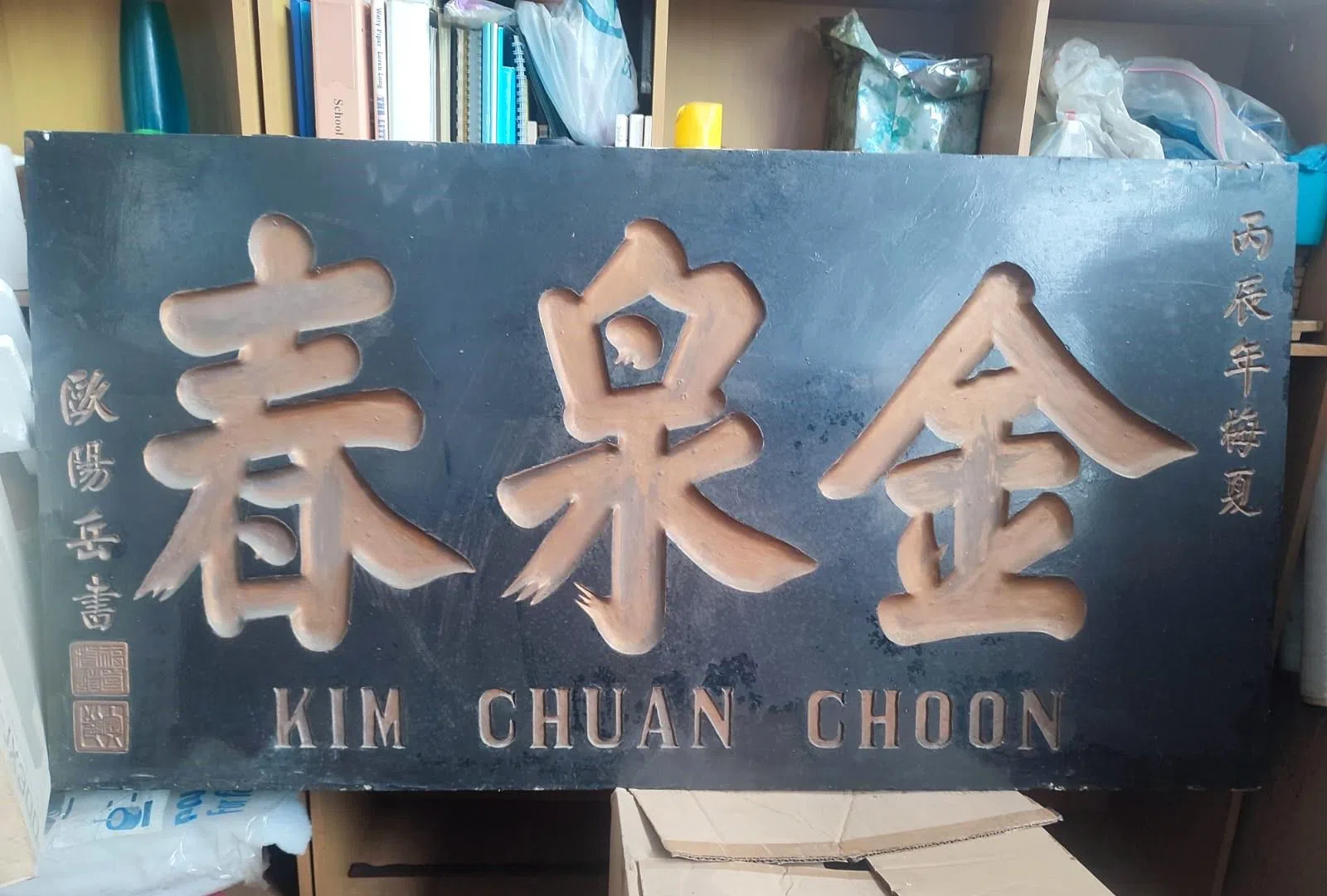 张逢春找出这块老招牌，右边刻着丙辰年（1916年），由欧阳岳书写。（受访者提供）