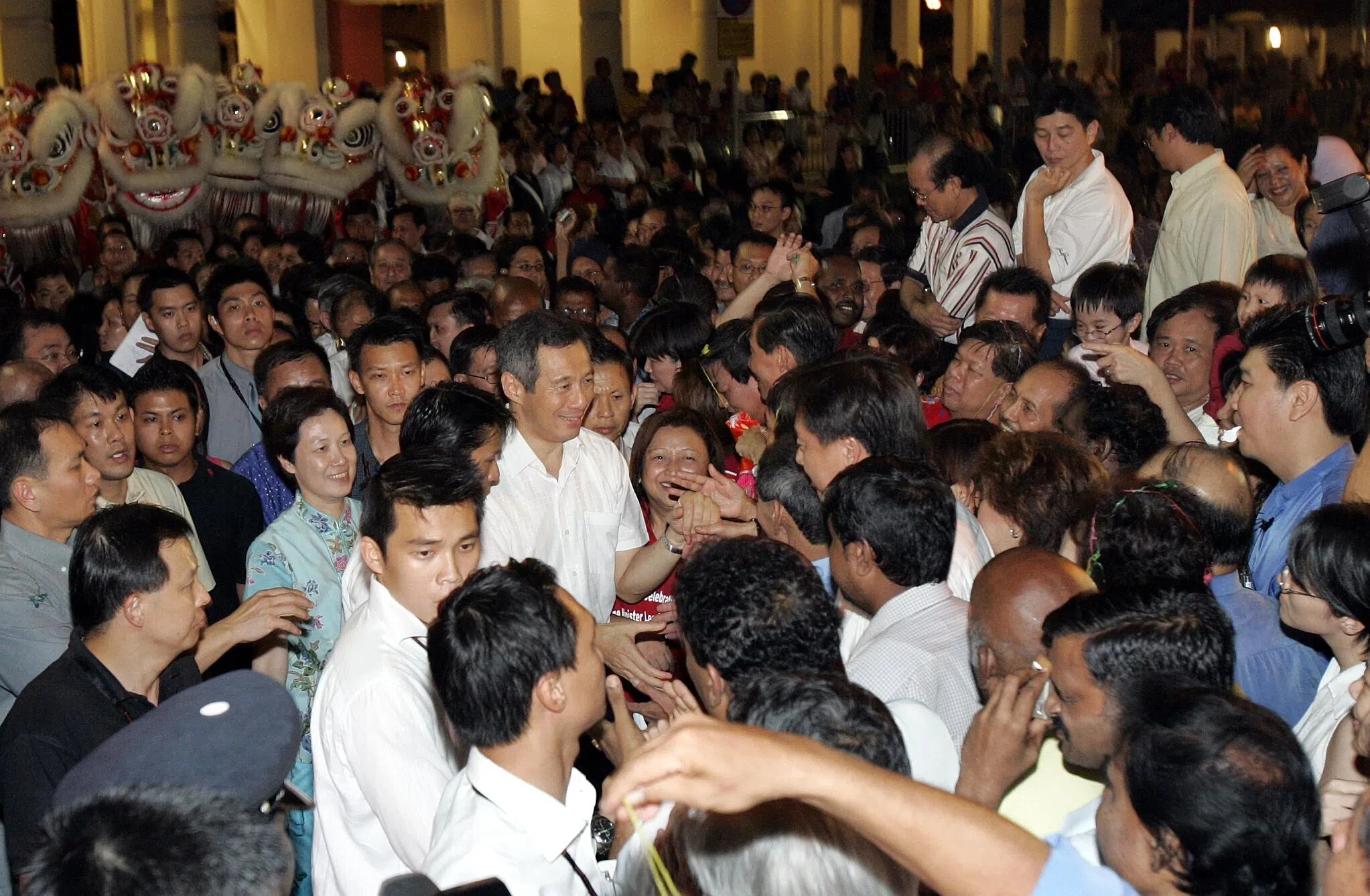 李显龙总理（中间白衣者）在宣誓就职仪式结束后，到德义区会见居民，民众蜂拥而上，希望与新任总理握手。（档案照片）