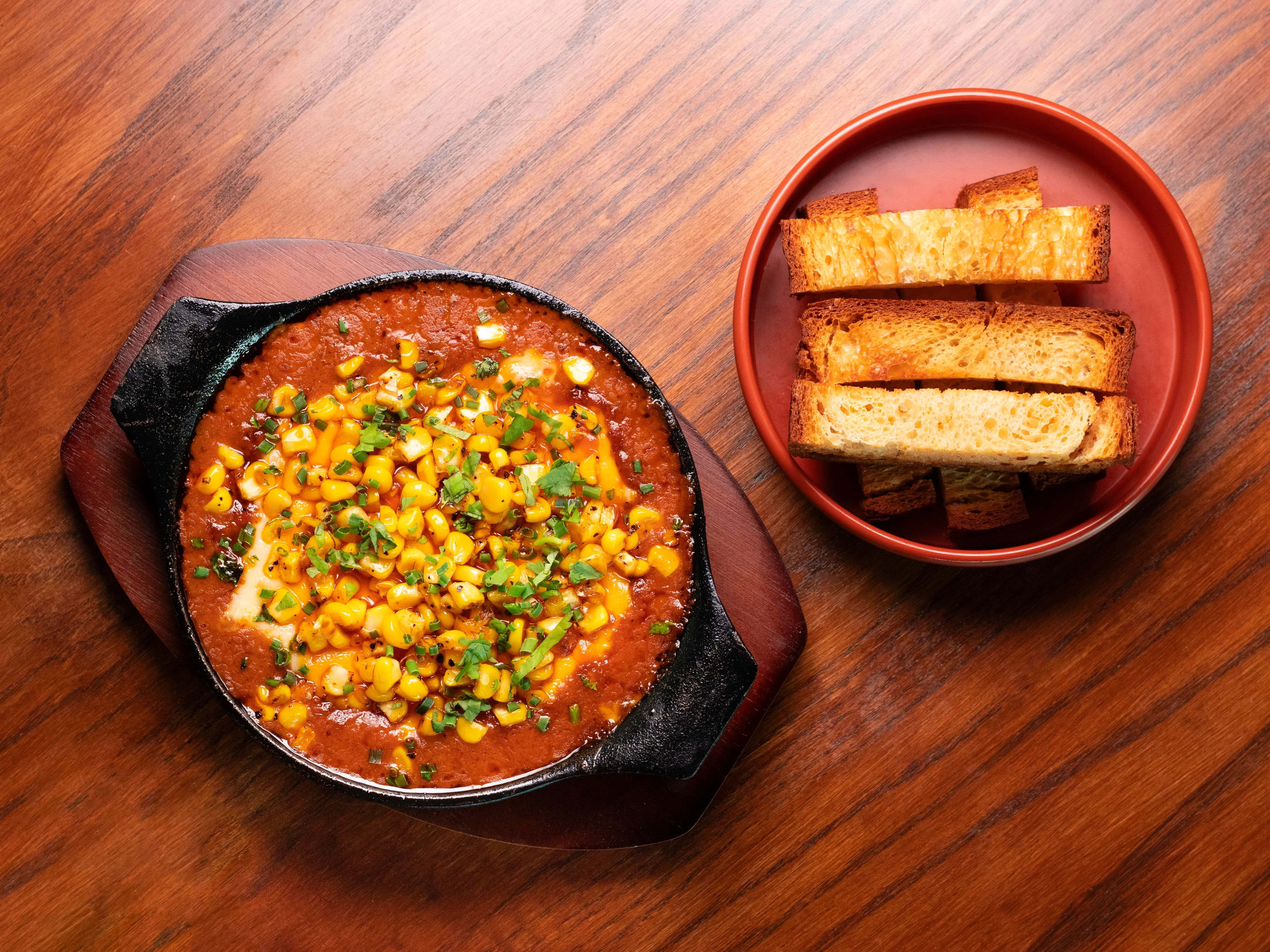 Queso Fundido以热铁锅盛装融化的芝士、玉米与黑豆，搭配松软布里欧修面包享用。（餐馆提供）