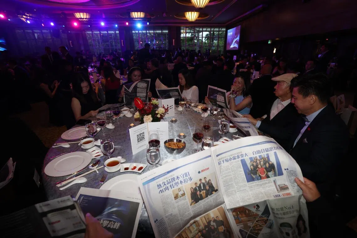 颁奖典礼开始之前，与会者翻阅《联合早报》为2025年新加坡金字品牌奖制作的特辑。（陈斌勤摄）