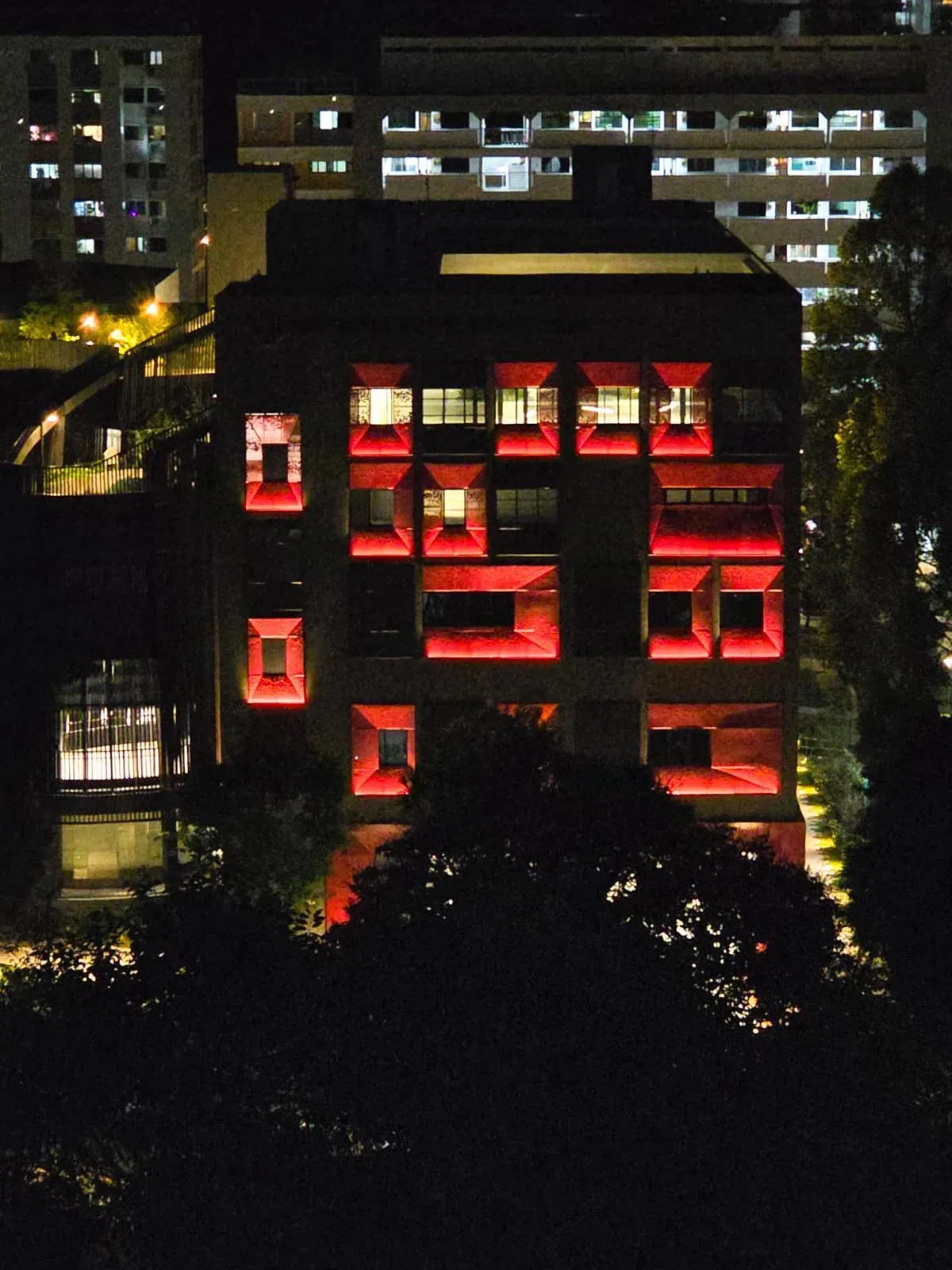 吉巴督东民众俱乐部外观红色框架表面布满细小圆孔，夜间灯光亮起后透出红色光芒，在周边组屋区格外醒目。（受访者提供）