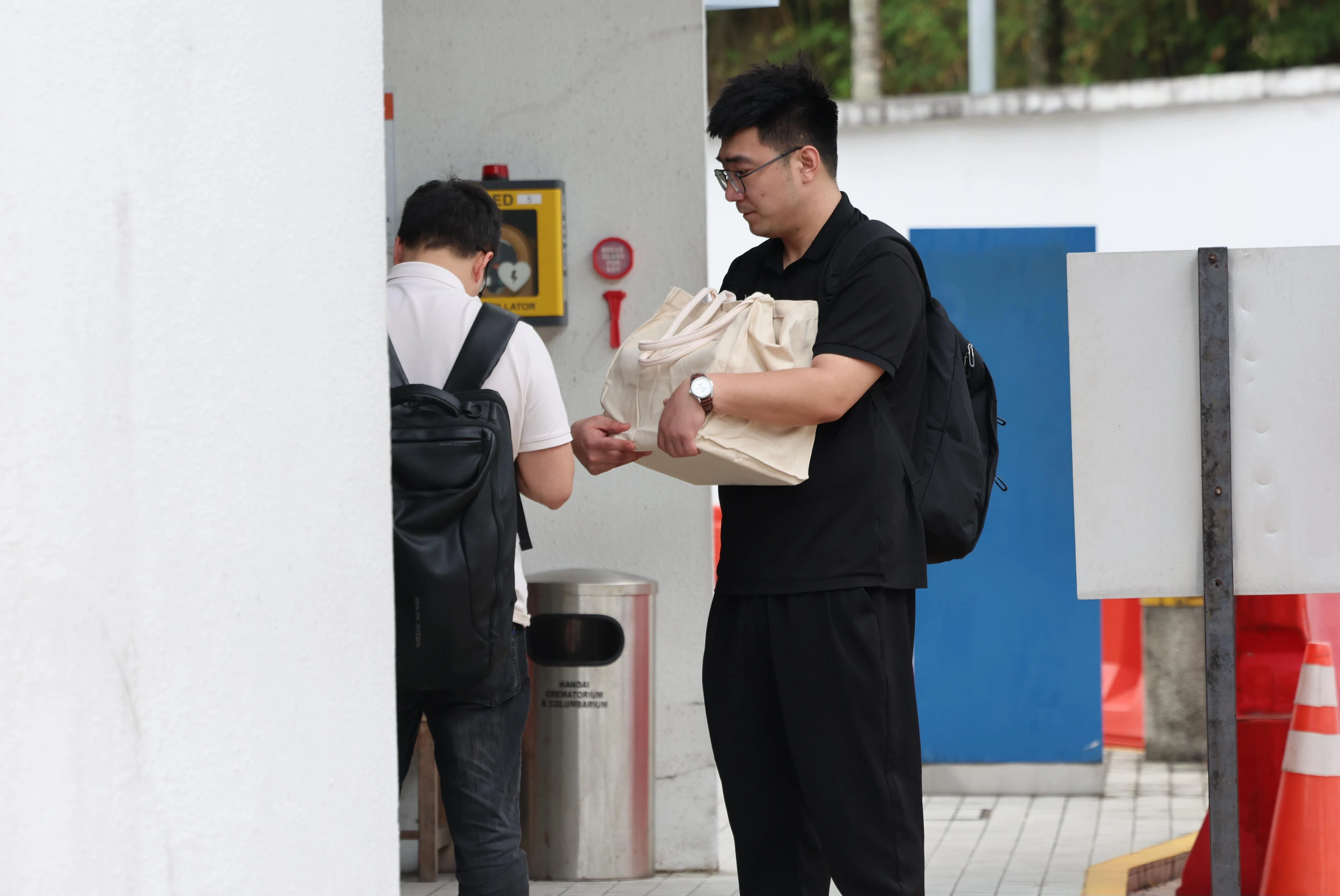 死者蒋欣琳的许姓丈夫（右）在舅子的陪同下，到万礼火化场把她的骨灰捡进骨灰瓮。（梁麒麟摄）
