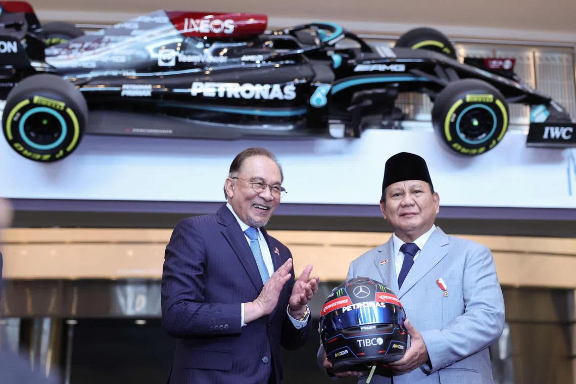 印尼总统普拉博沃（右）星期一在吉隆坡国油双峰塔与马国首相安华会面时，获赠马赛地—AMG马石油（Mercedes-AMG Petronas）F1车队的头盔作为纪念品。（法新社）