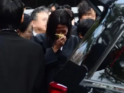 田慧振目送丈夫的棺木上灵车，忍不住低头痛哭。（互联网）