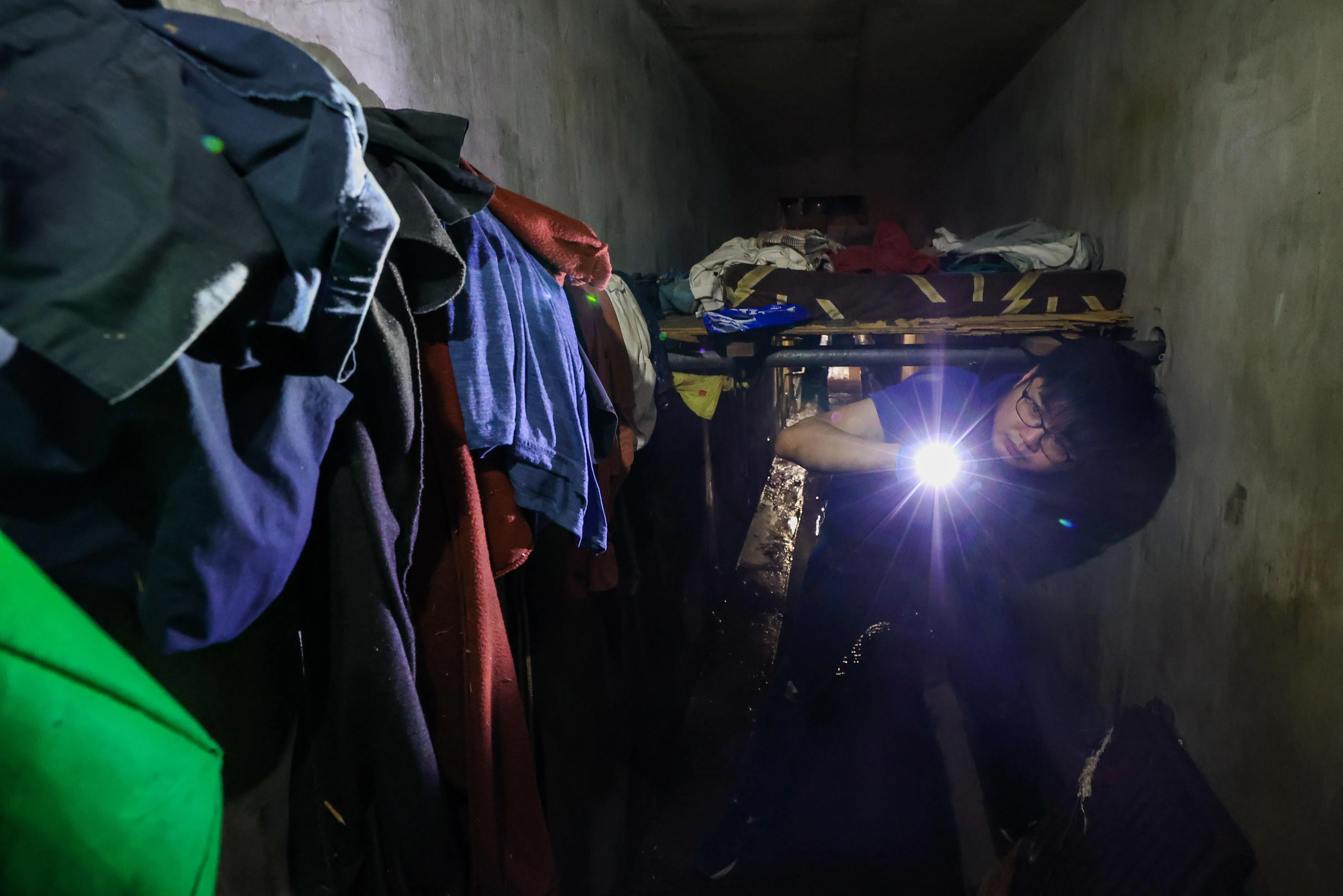 除了架设床榻，下水道墙壁上还挂满了衣服和鞋子等生活用品。（陈斌勤摄）