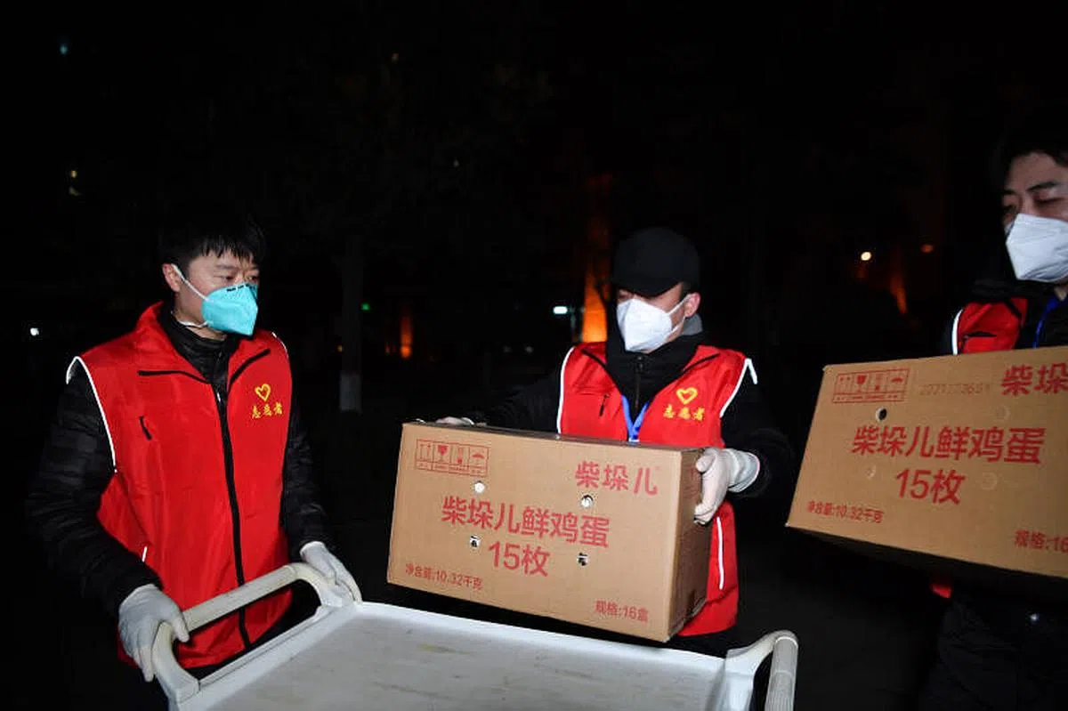 在西安曲江风景线小区，志愿者运送免费生活物资。（新华社） 
